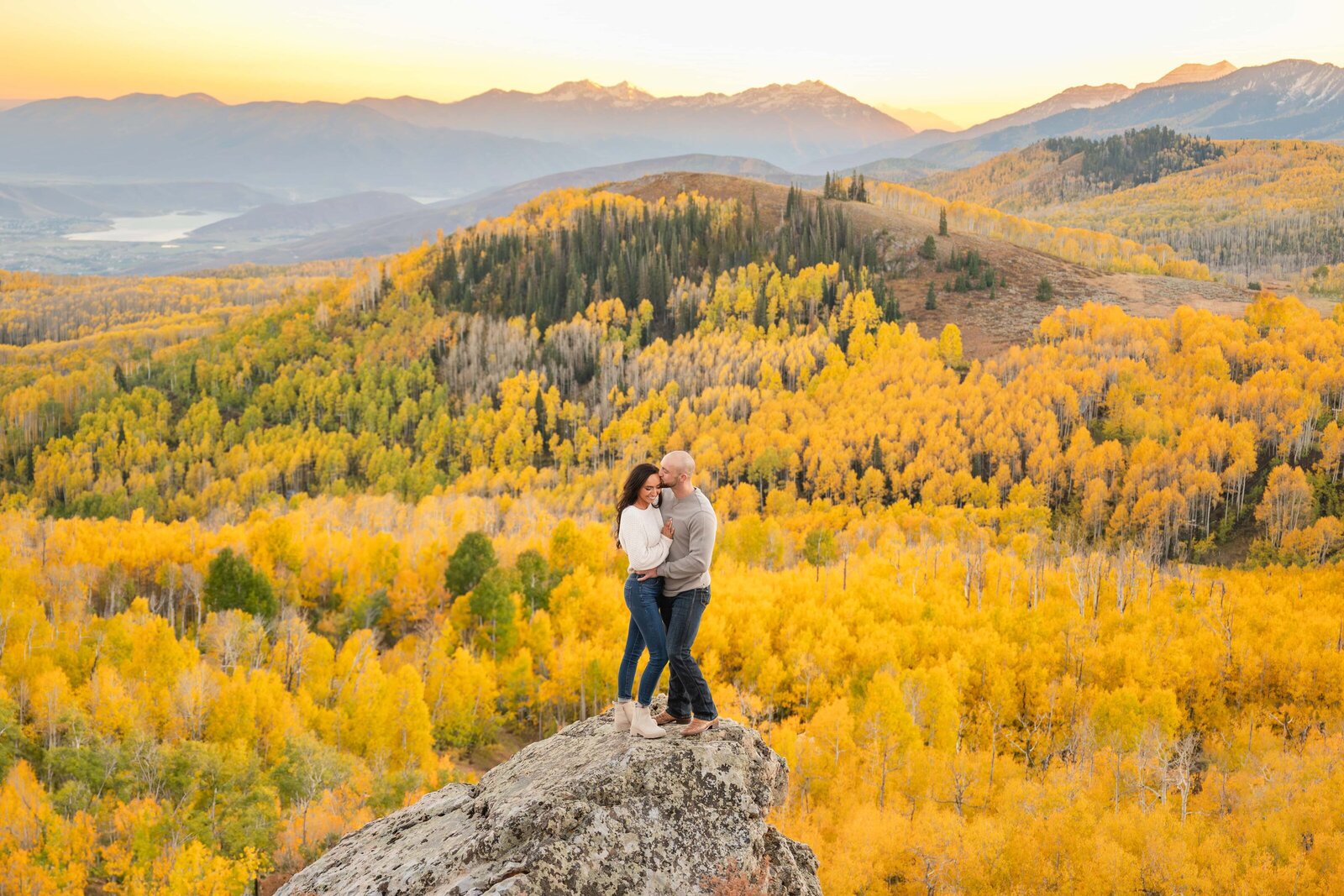 Couple in Park City surrounded by fall leaves with a view of mountains