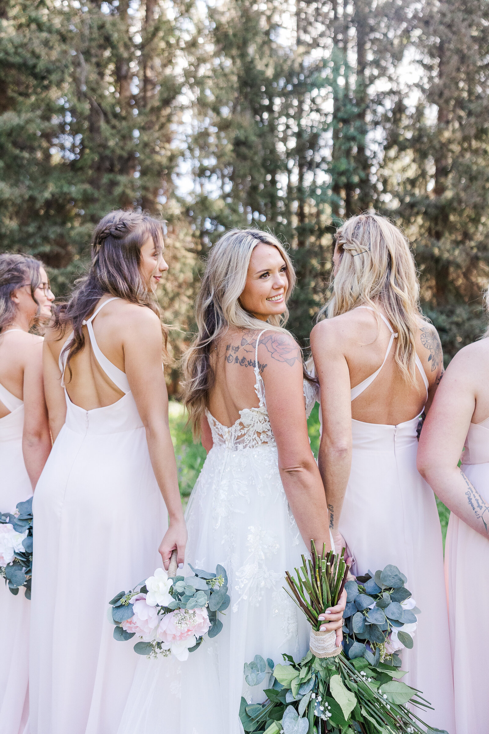 Bridemaids facing away from camera and bride turning her head slightly to look at camera in Arrowhead Lodge