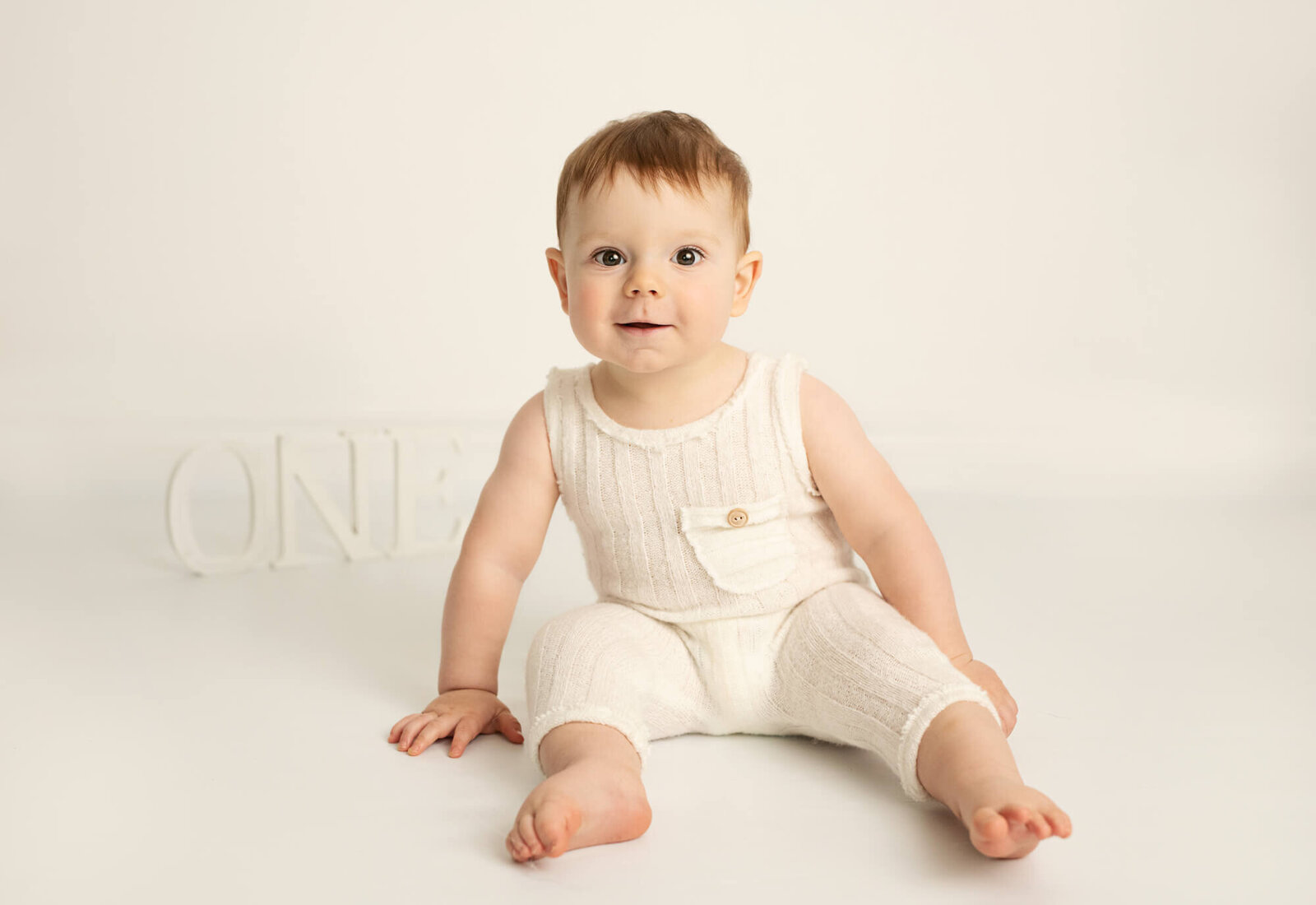 One year old baby with white romper and white background