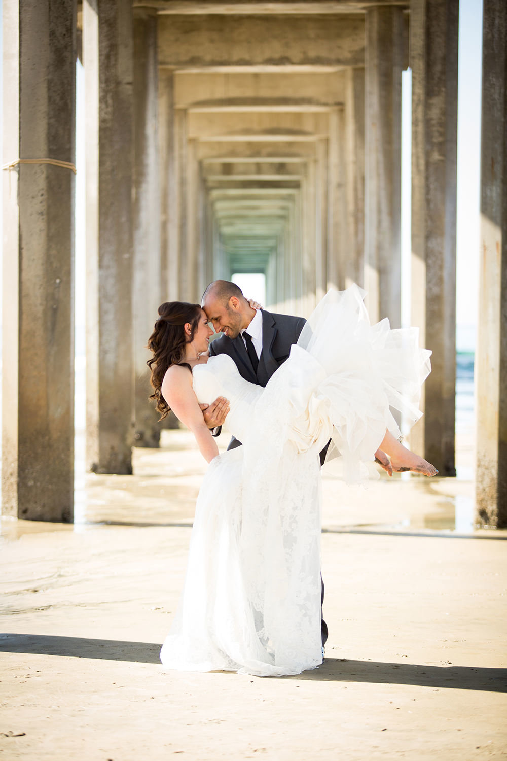 groom holding bride by scripps pier