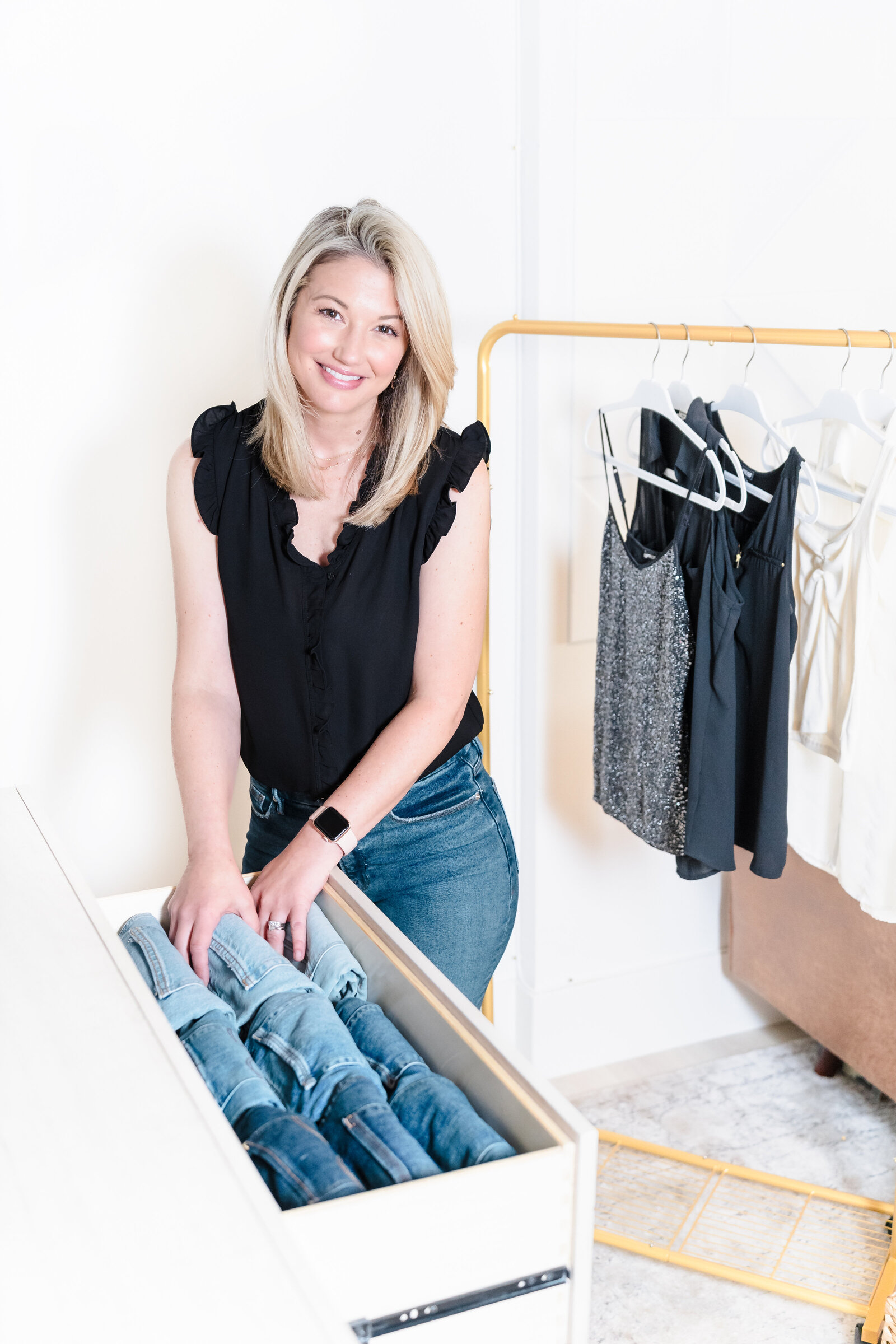 brand photo of a professional organizer posing close to a drawer full of jeans pants