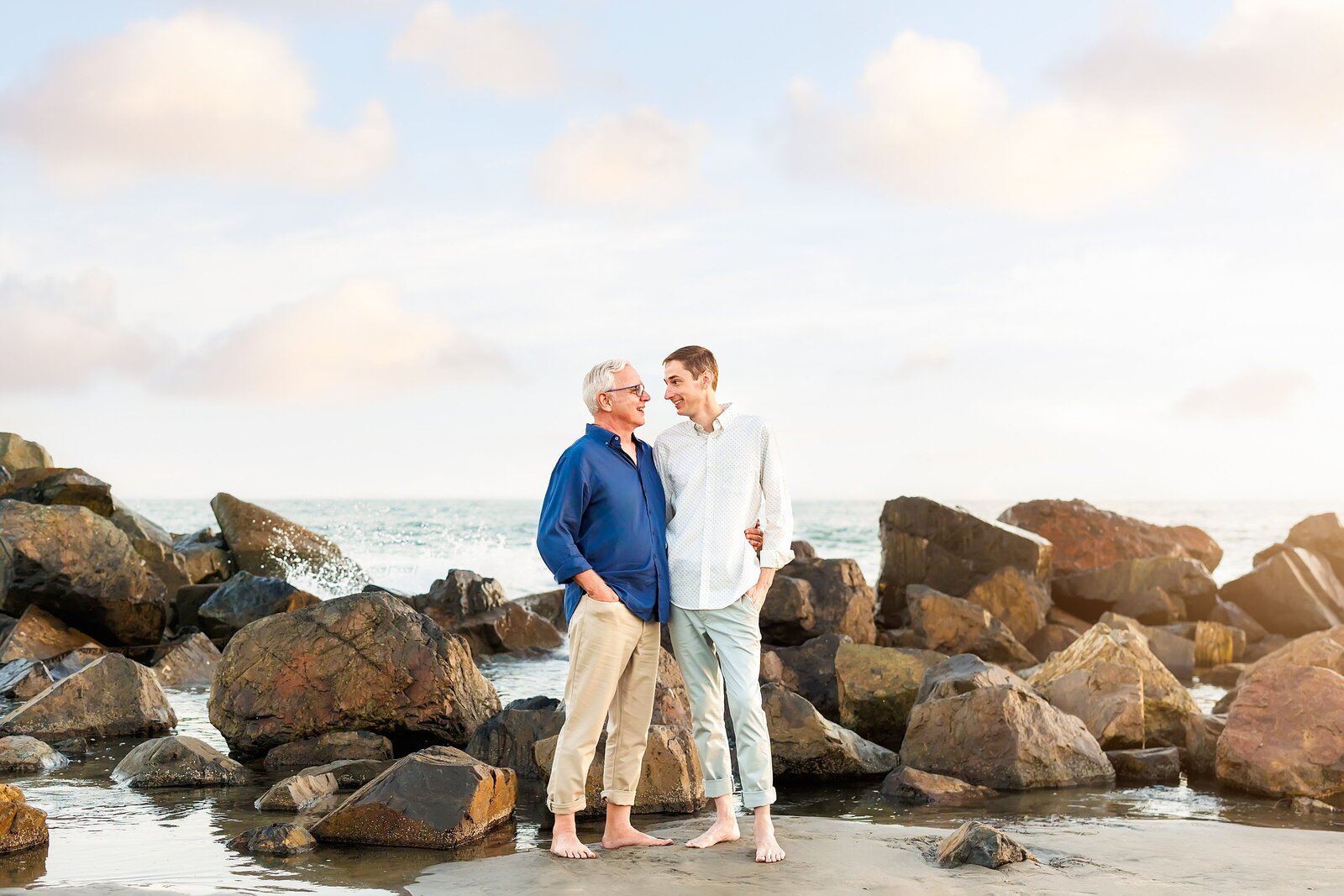 Two married men posing in front of the rock jetty on the beach at the Hotel Del Coronado