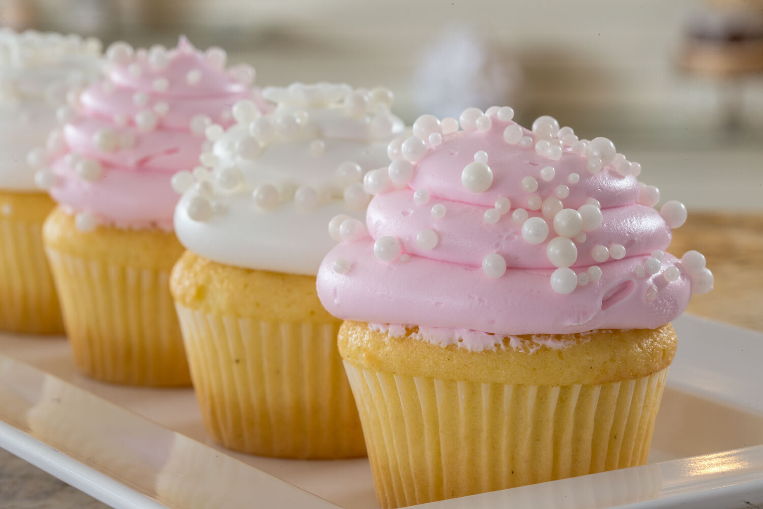 Cupcakes with pink and white frosting topped with pearl sprinkles