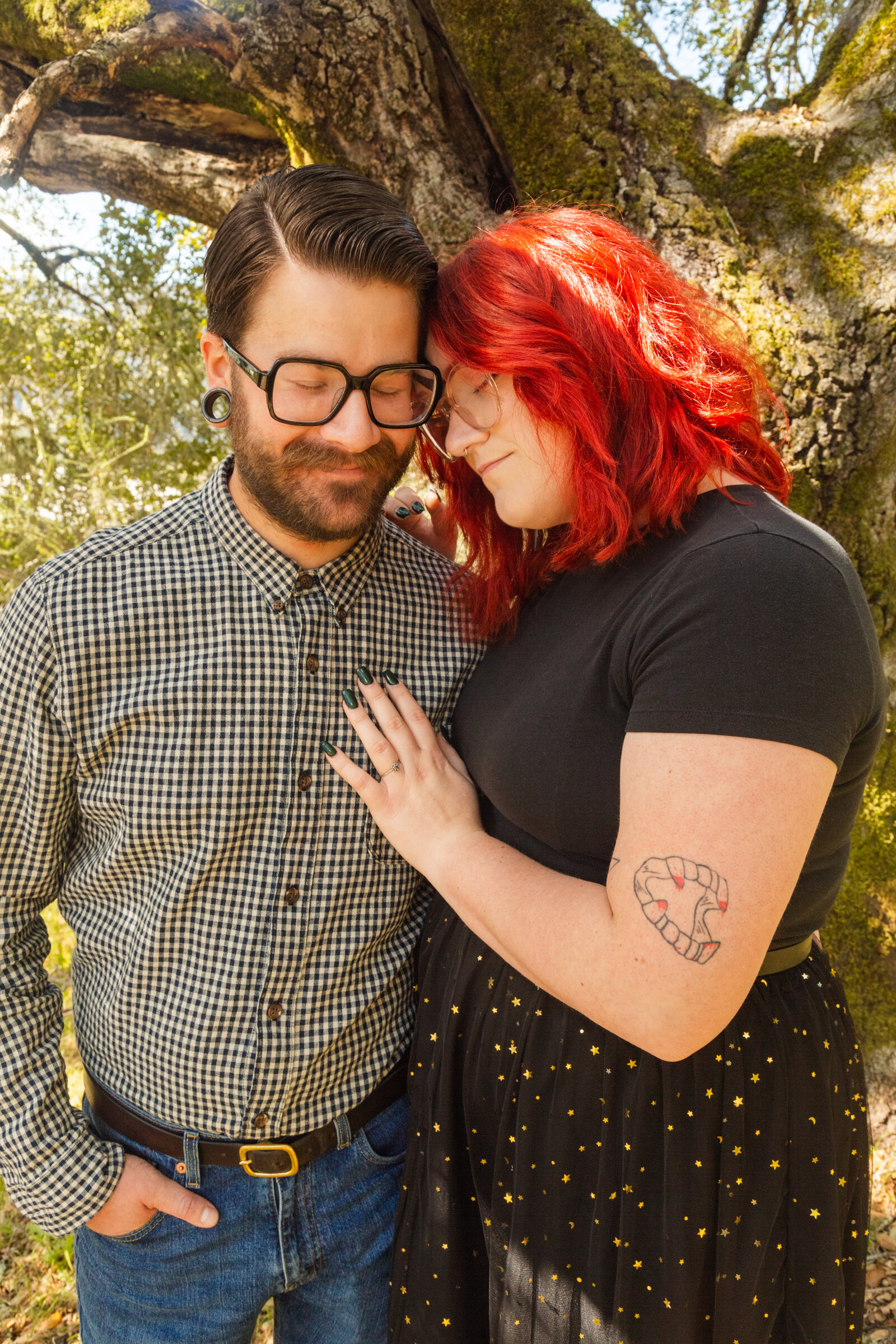 An tattooed engaged couple poses for photos in a redwood forest in Santa Cruz, Ca.