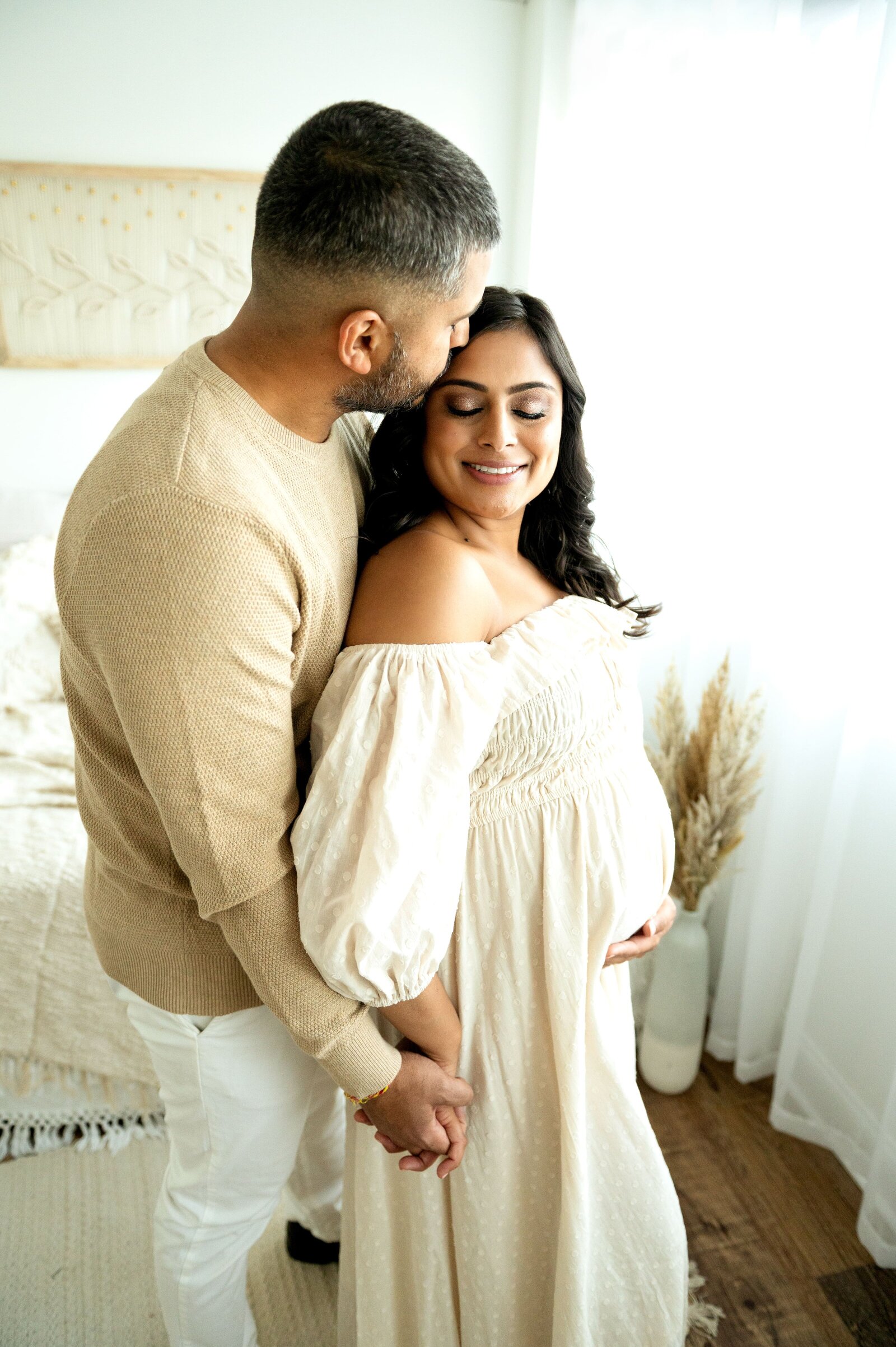 pregannt woman in a cream dress with her husband doing maternity photo