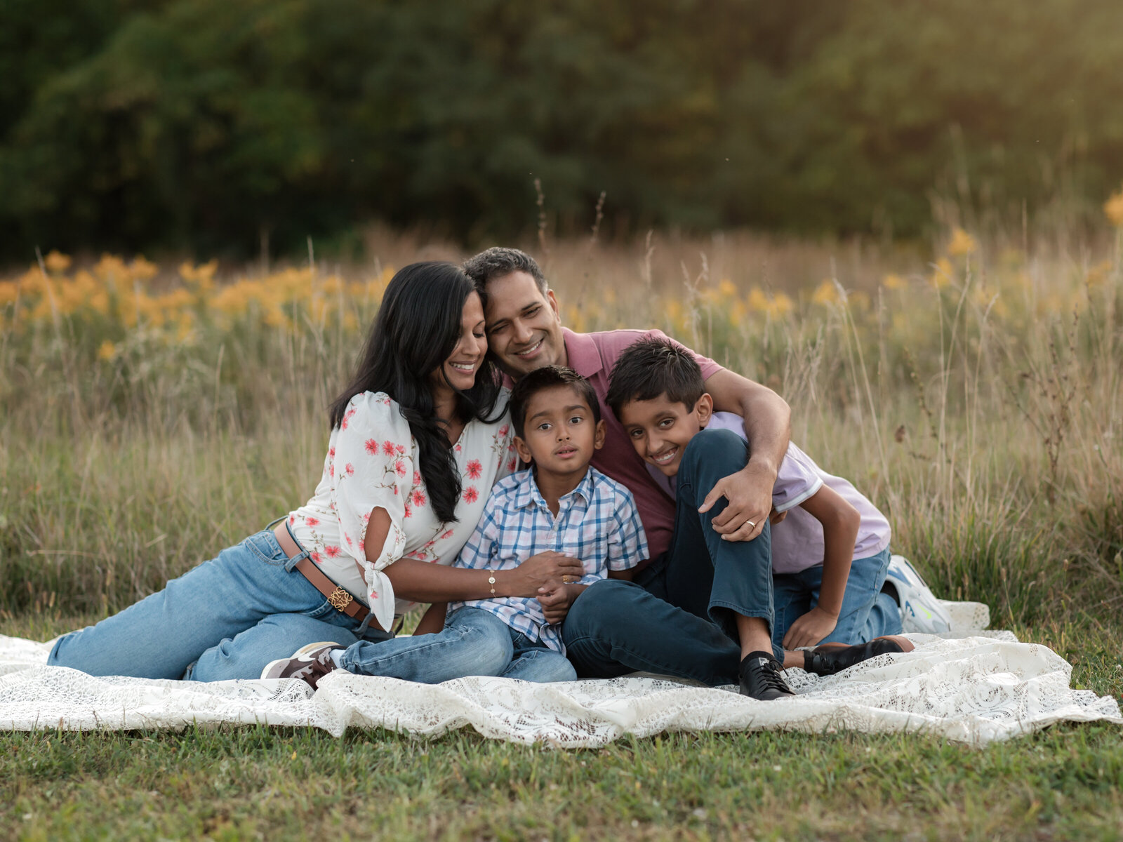mom, dad and two sons sitting in park for family photos 