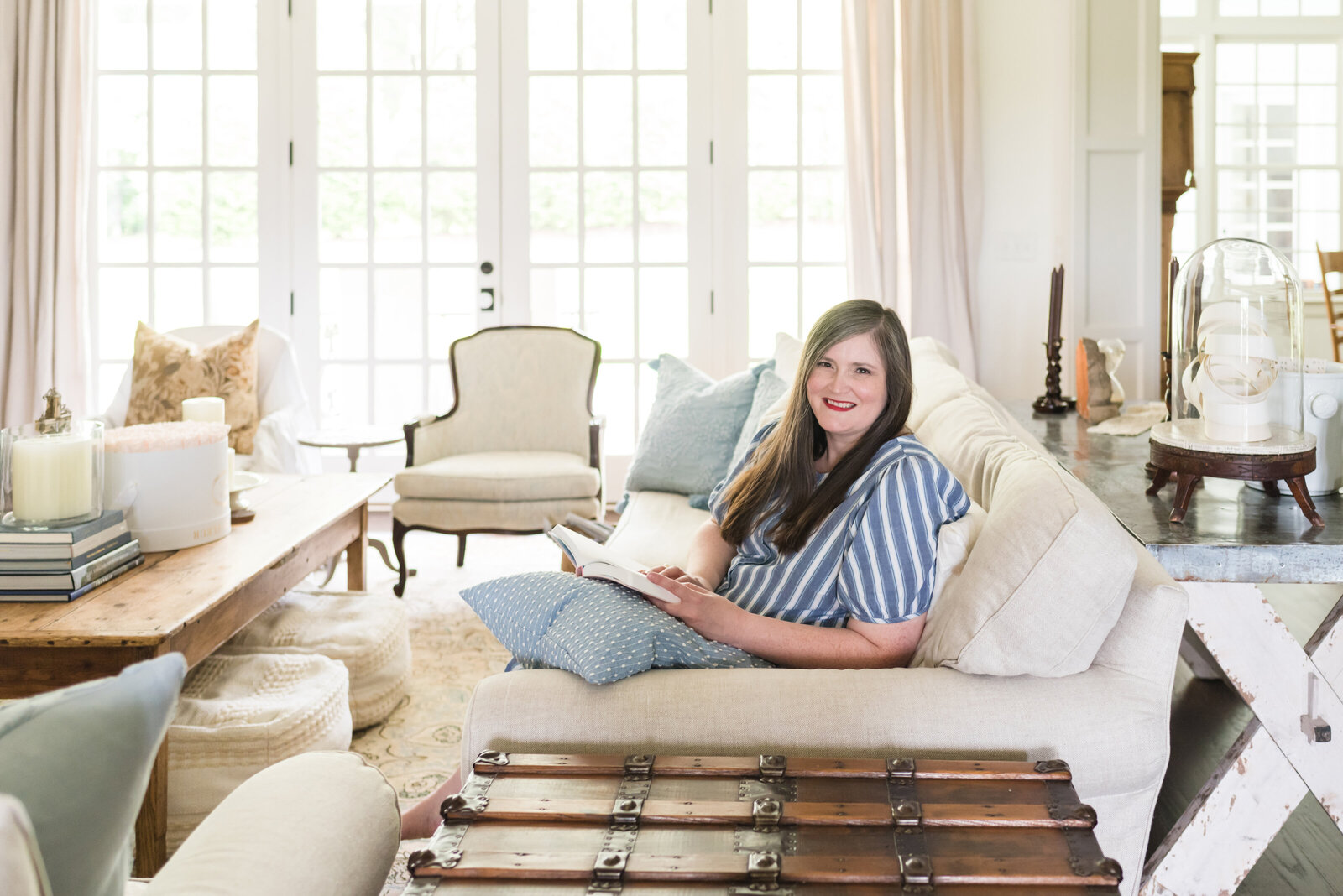 Inherited and Co. founder, Lauren Klein, sits in her light-filled living room in a blue and white striped dress