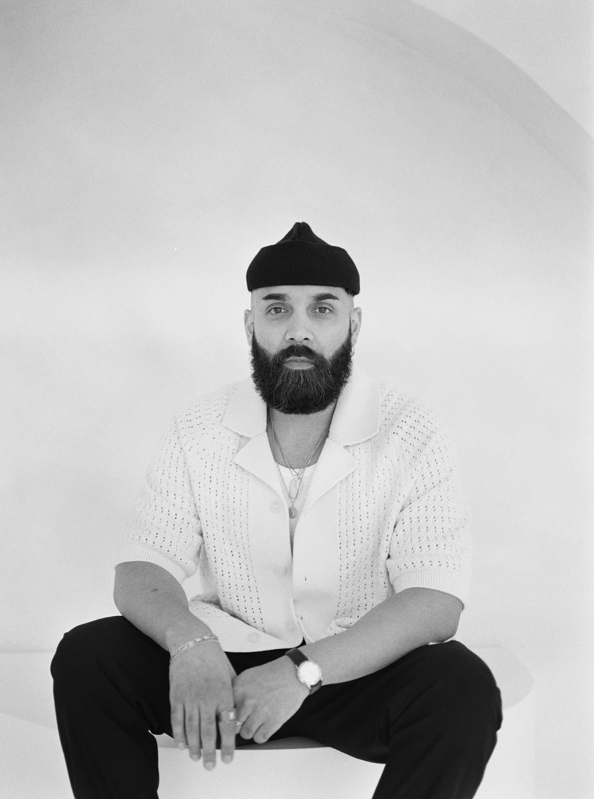 Professional black-and-white headshot of a bearded man wearing a stylish knit sweater and beanie in Washington, DC.