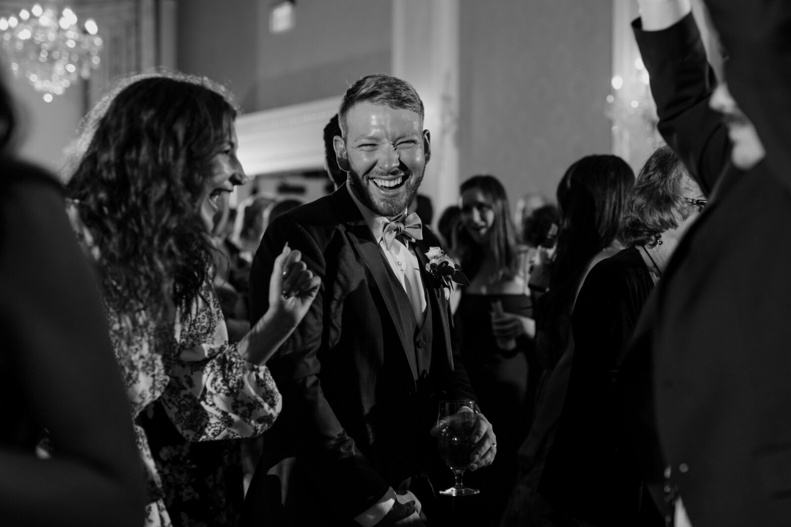 A groom laughs while dancing at a wedding reception in a hotel