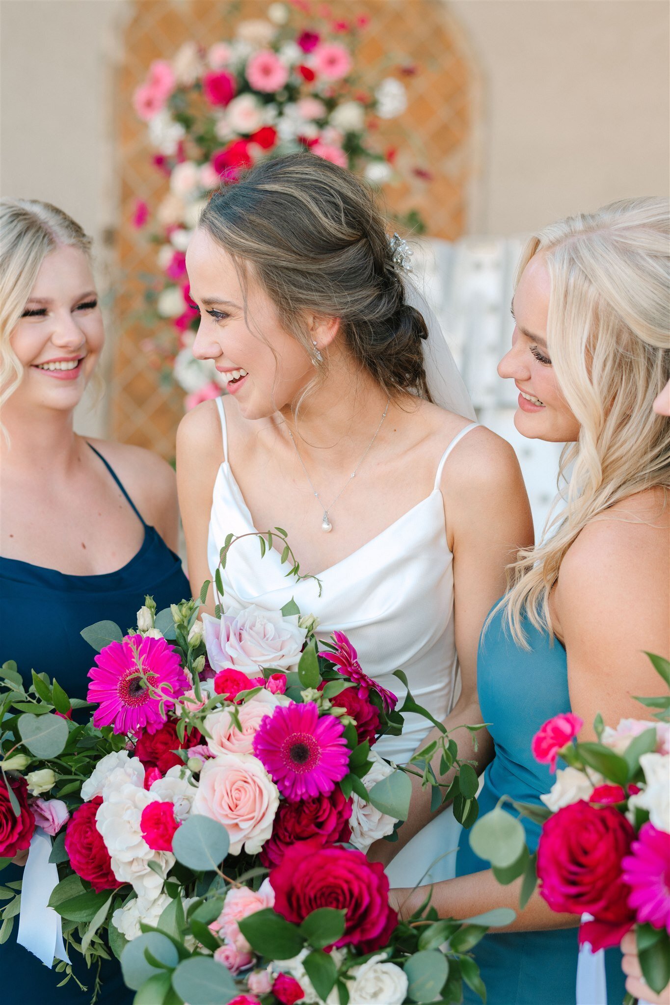 bridesmaids wearing blue dresses with bright pink flower bouquetws