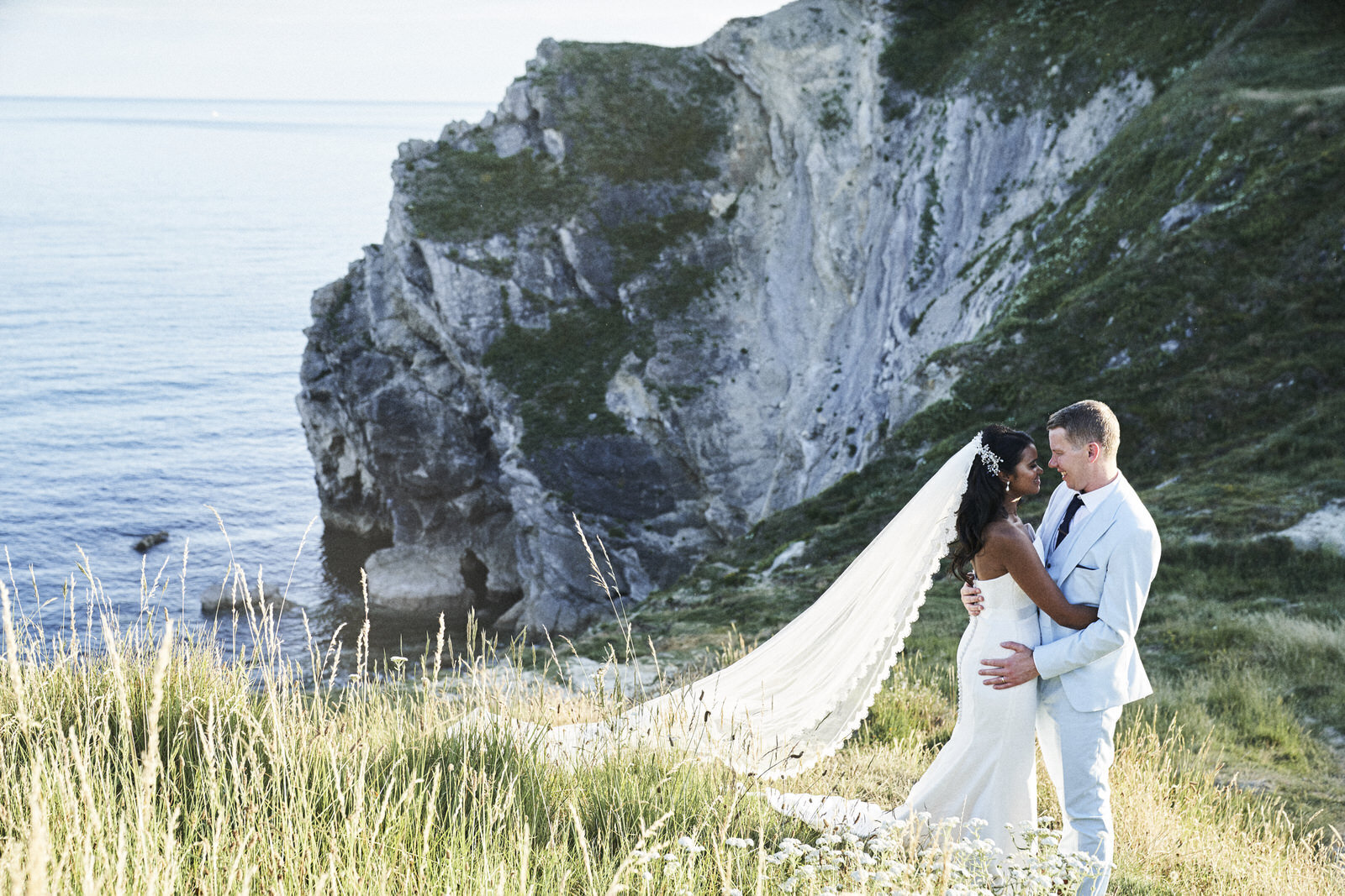 Bride and groom posing for portraits on grassy cliffside