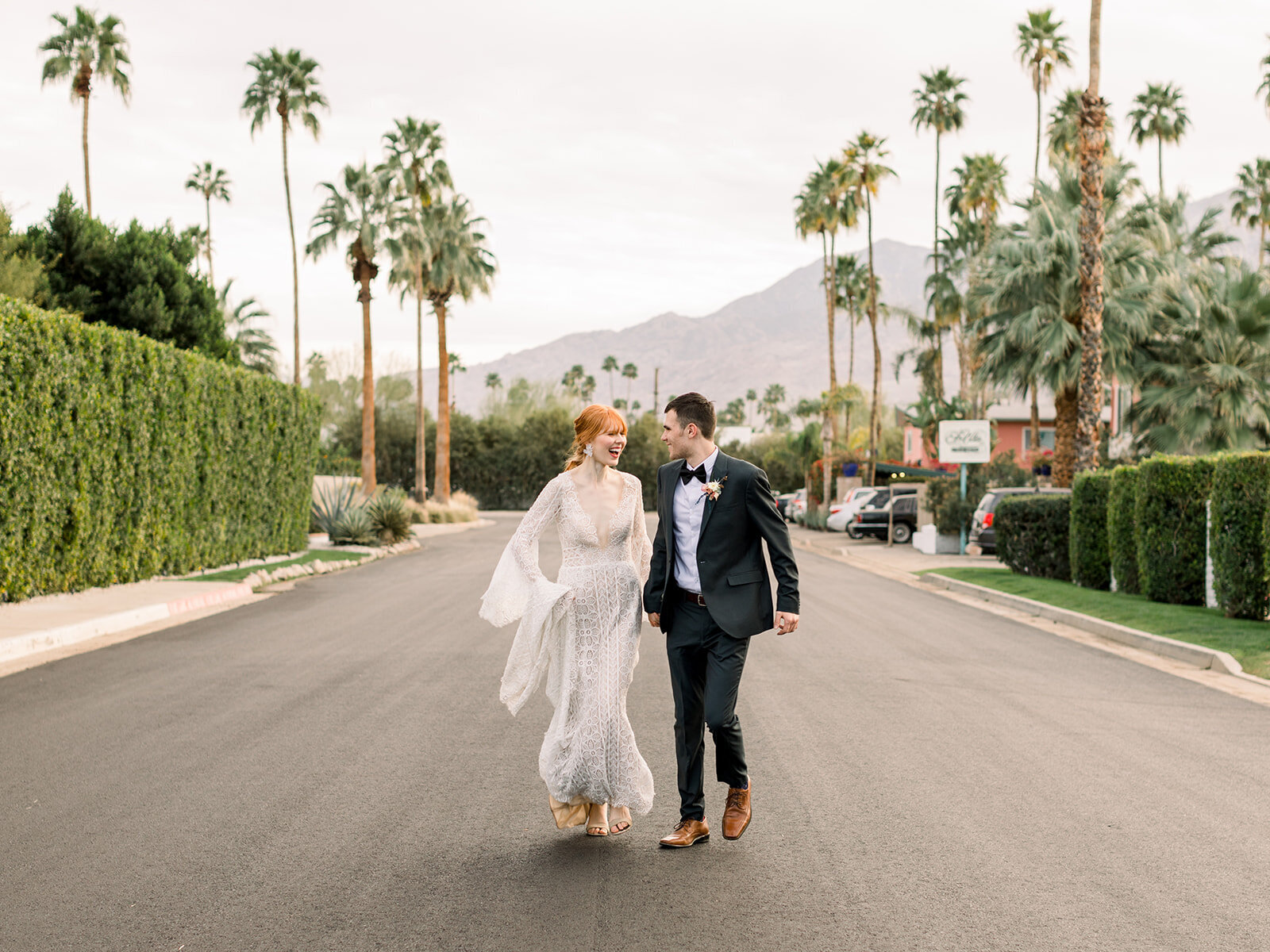 Kohnur fine art couple portrait with bride in natural glowing makeup and romantic updo, wearing a sheer gown, posing outside a Tuscan villa entryway.