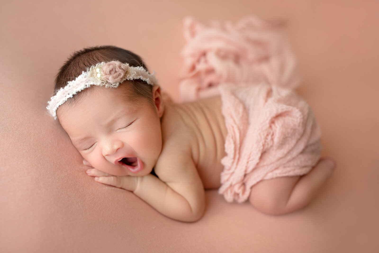 A peaceful newborn baby is posed on a soft pink pastel bean bag. This heartwarming image, captured at Little Legacies Studio in Phoenix, Arizona, beautifully preserves the innocence and charm of your newborn's early days. Newborn posing