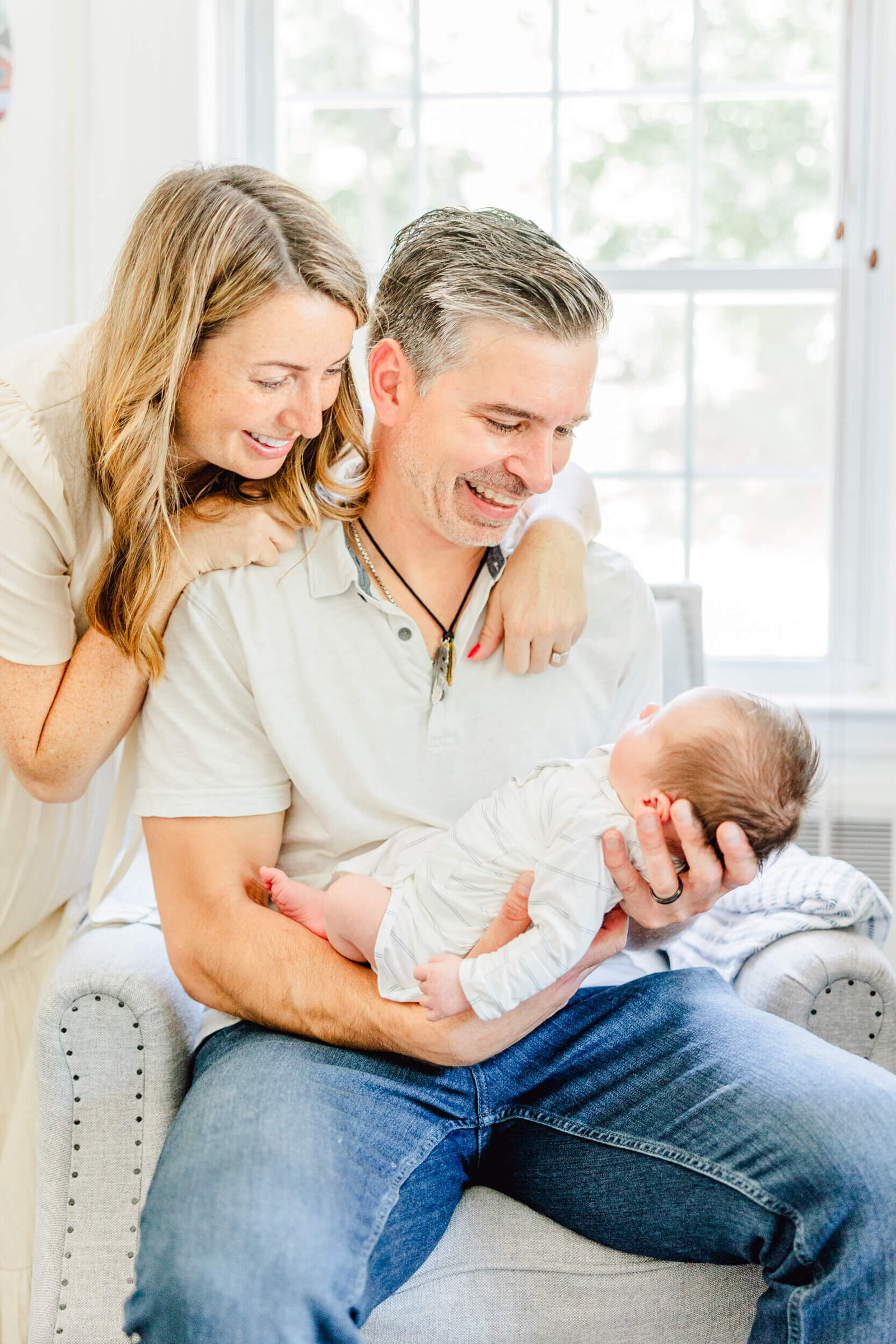 Mom smiles over Dad's shoulder at newborn