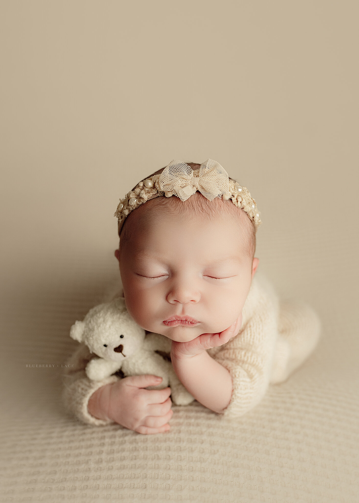 sweet baby girl posed in oswego ny newborn photography studio in cream and neutrals with modern art
