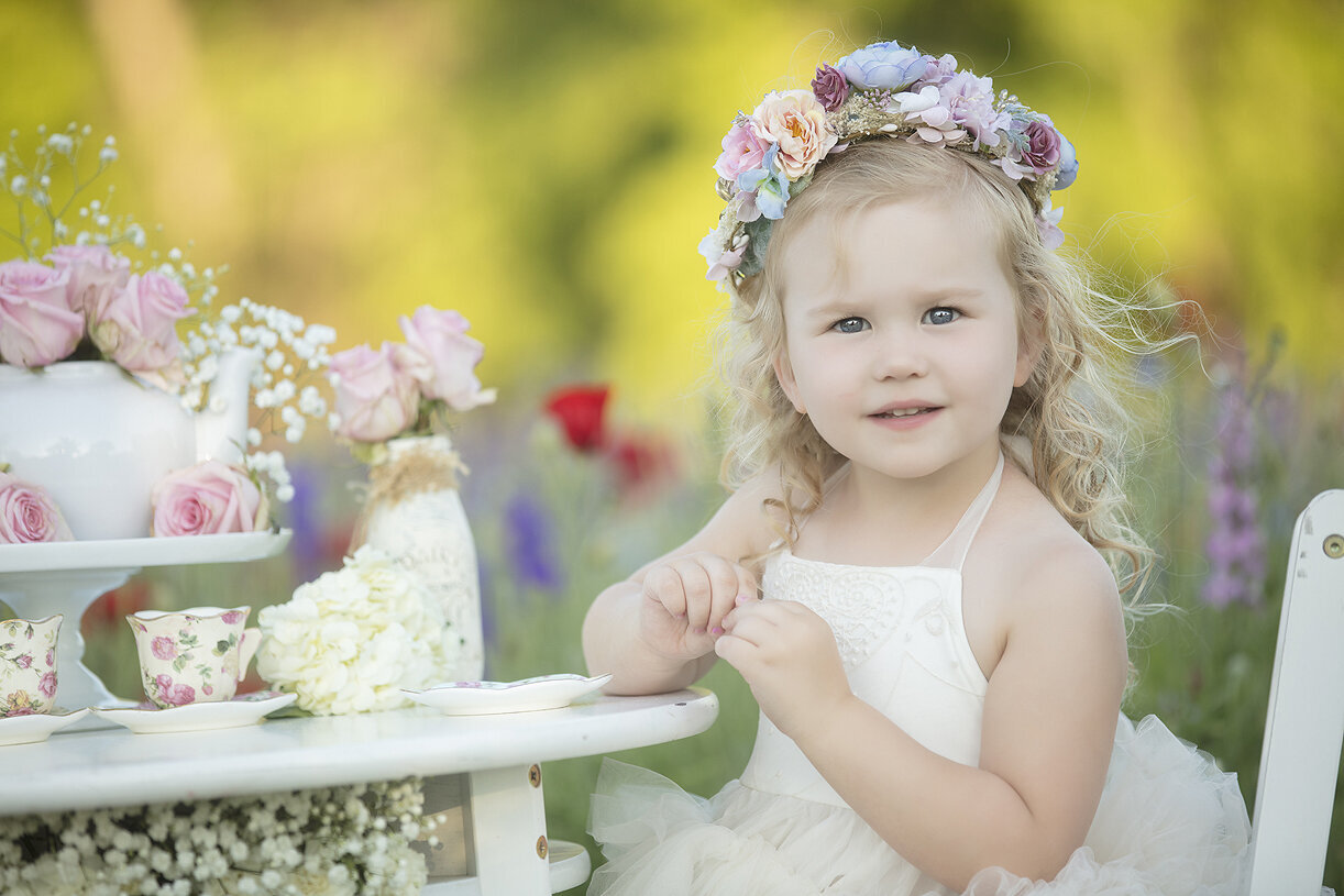 Little girl at tea party in flower field.