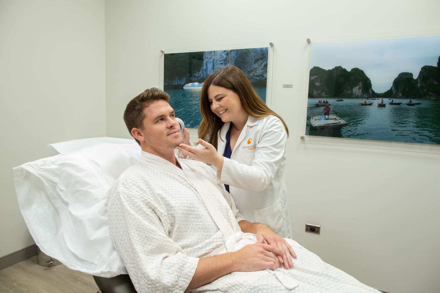Male patient smiling while a female provider examines his face in a clinic