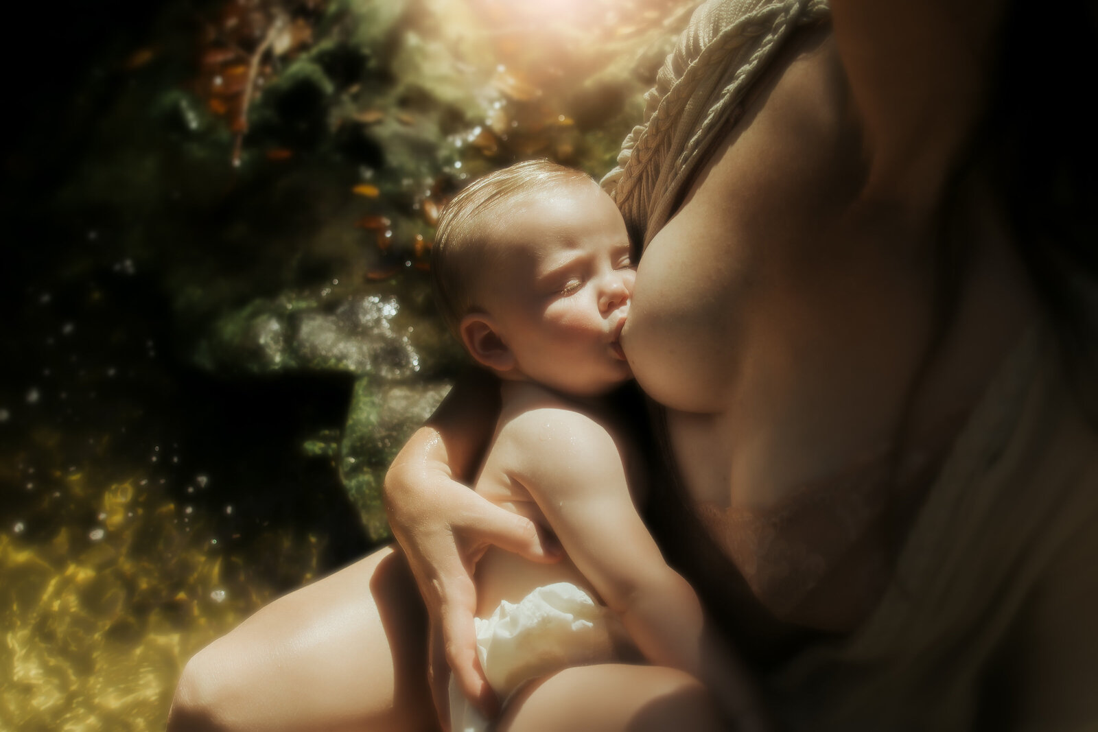 dreamy breastfeeding photo of a women and baby sitting in a creek in lithia springs fl