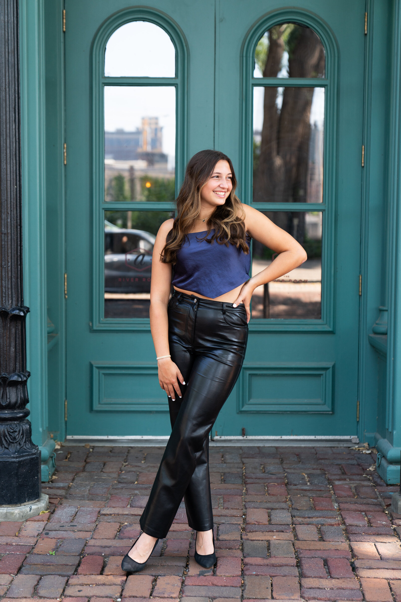 High school senior poses in front of blue doors during her senior pictures