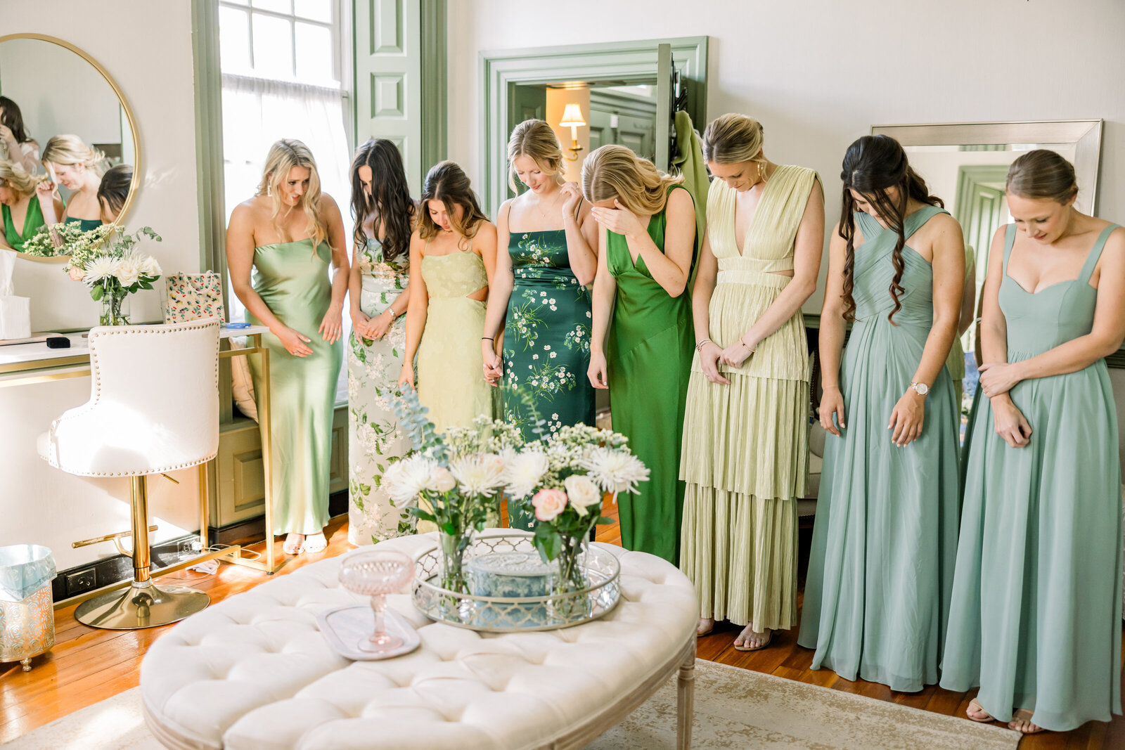 Bride’s emotional first look with bridesmaids dressed in beautiful floral prints with green tones, capturing a heartfelt and joyful wedding moment.