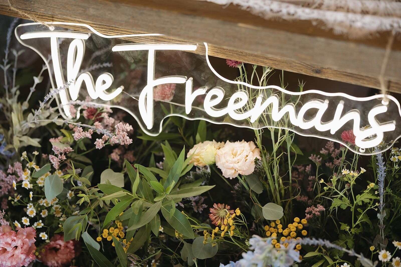 The Freemans neon sign over wildflowers at the sweetheart table