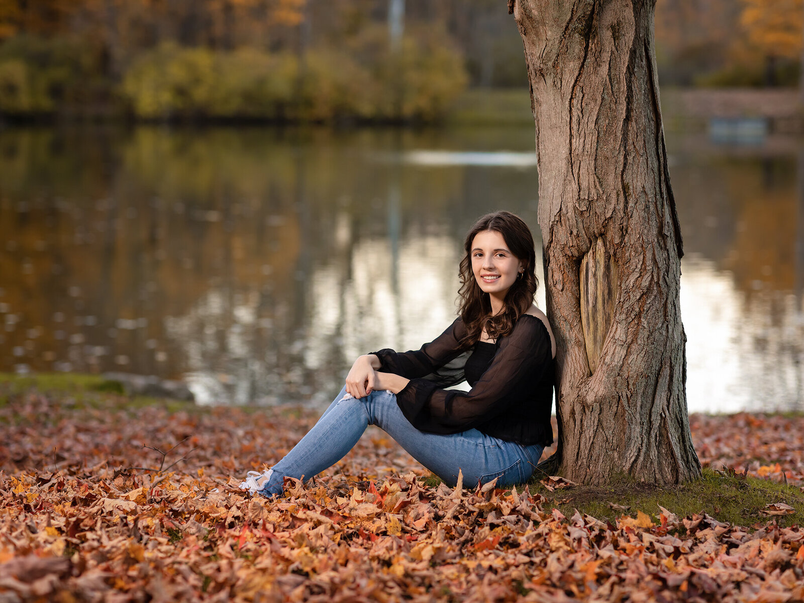 senior girl sitting against tree for photoshoot at furnace run park richfield