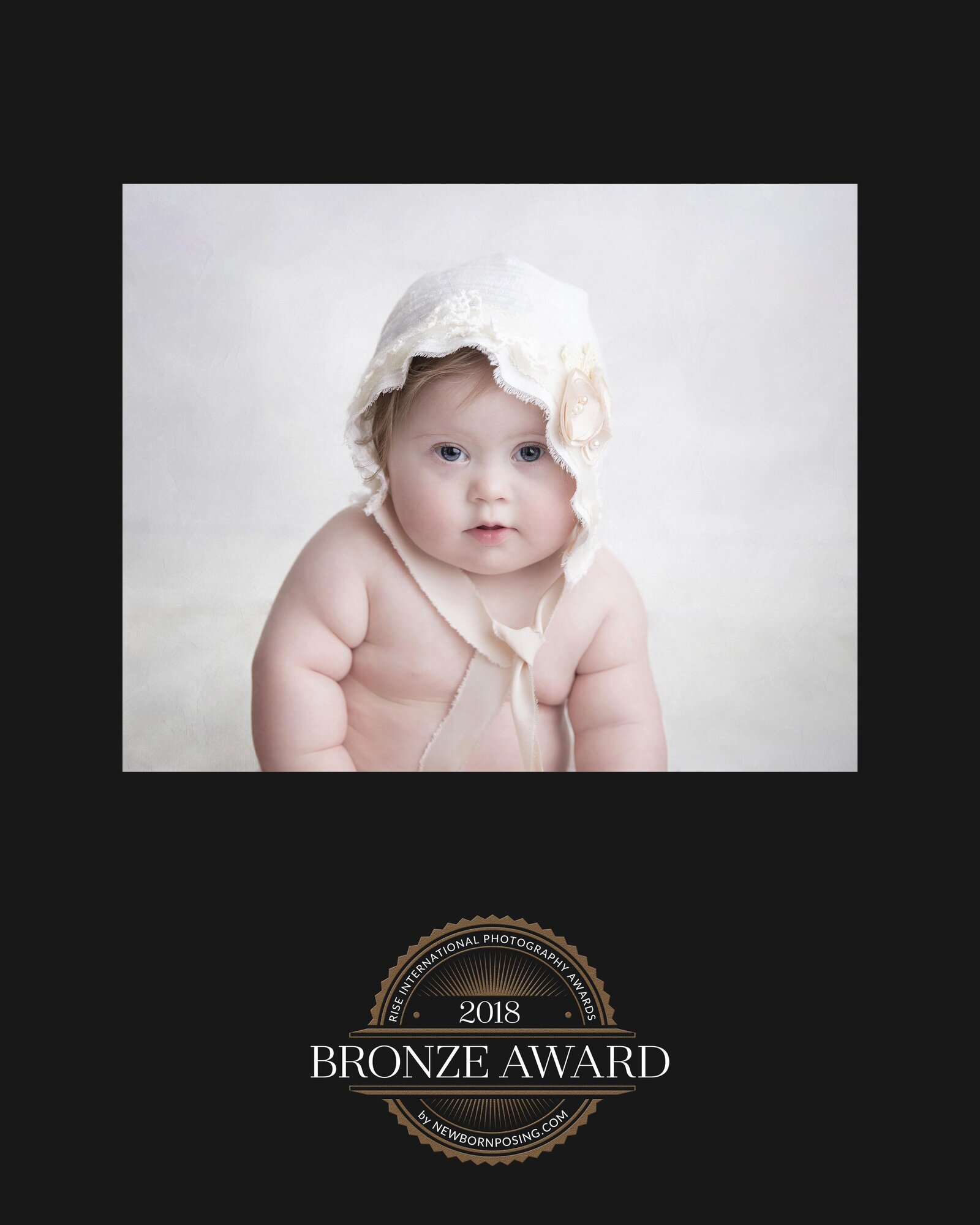 Baby girl sits with bonnet for her milesotne pictures in Murrysville.