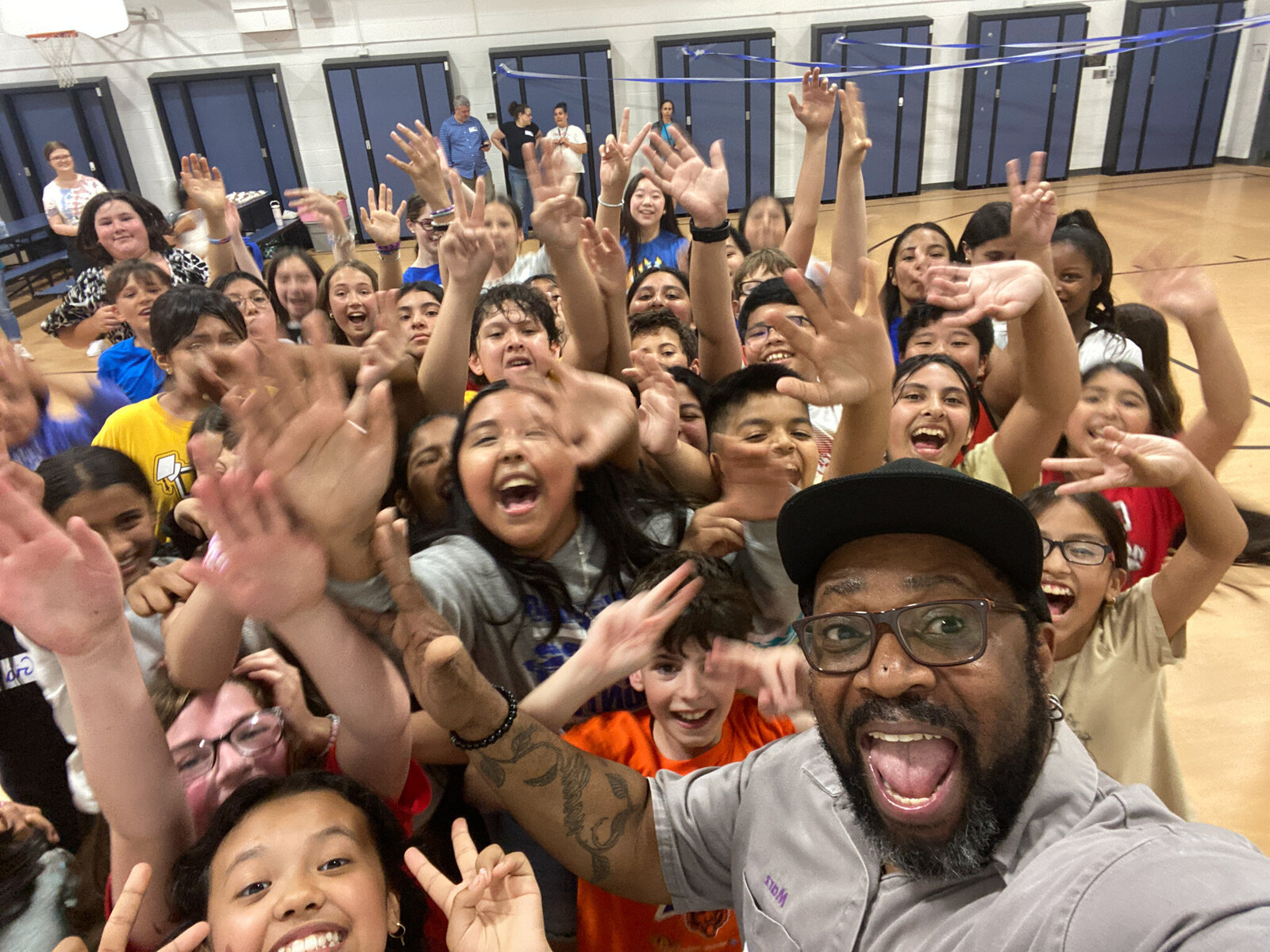 DJ taking a selfie with excited kids in a gym
