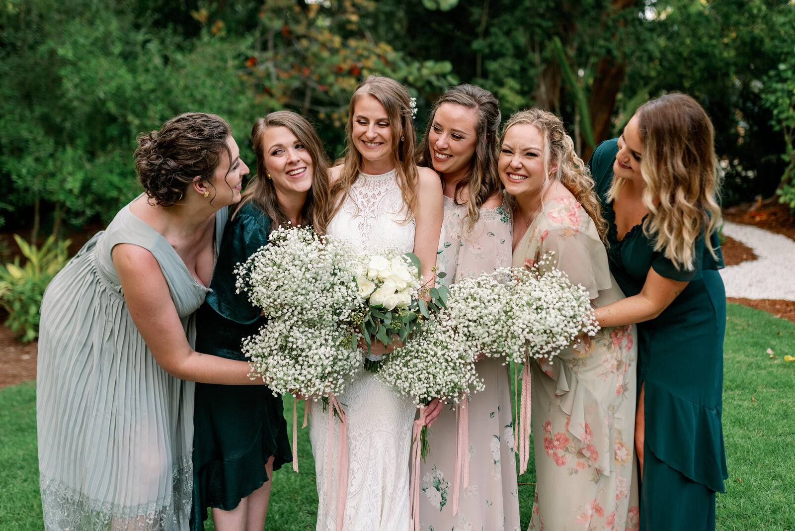 Bride and her bridesmaids hugging close together and smiling with their bouquets.