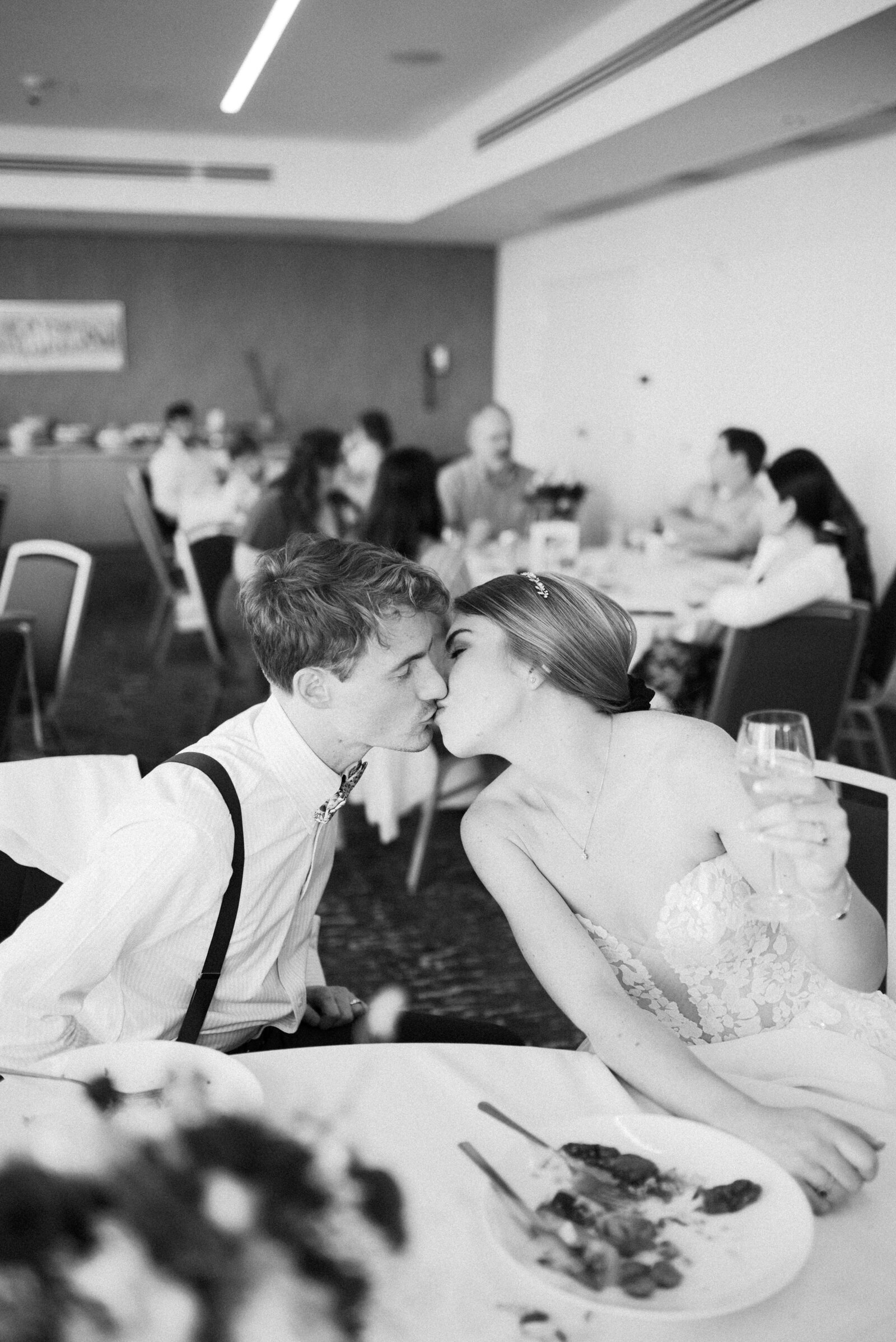 Bride and groom kissing at their table during their reception.