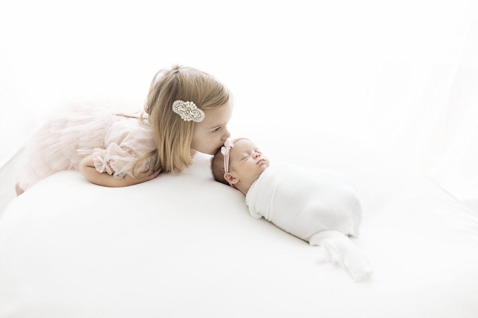 sister kissing baby sisters head philadelphia newborn photographer