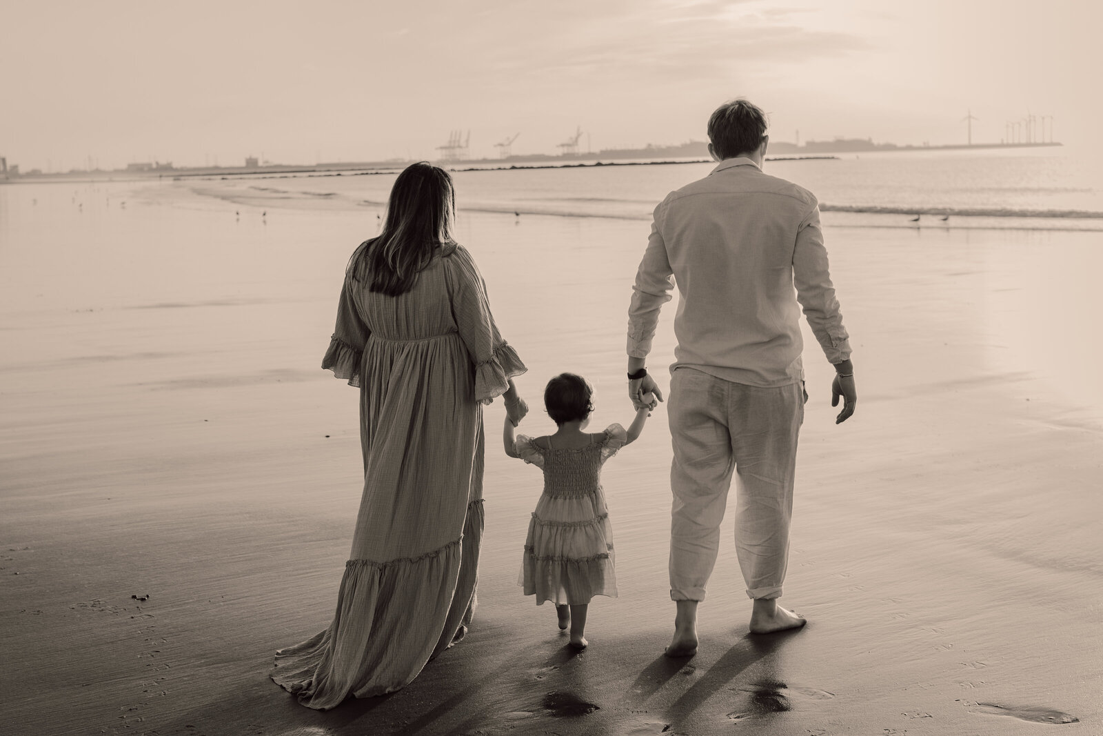 Gezin wandelt samen op het strand, hand in hand tijdens familie fotoshoot
