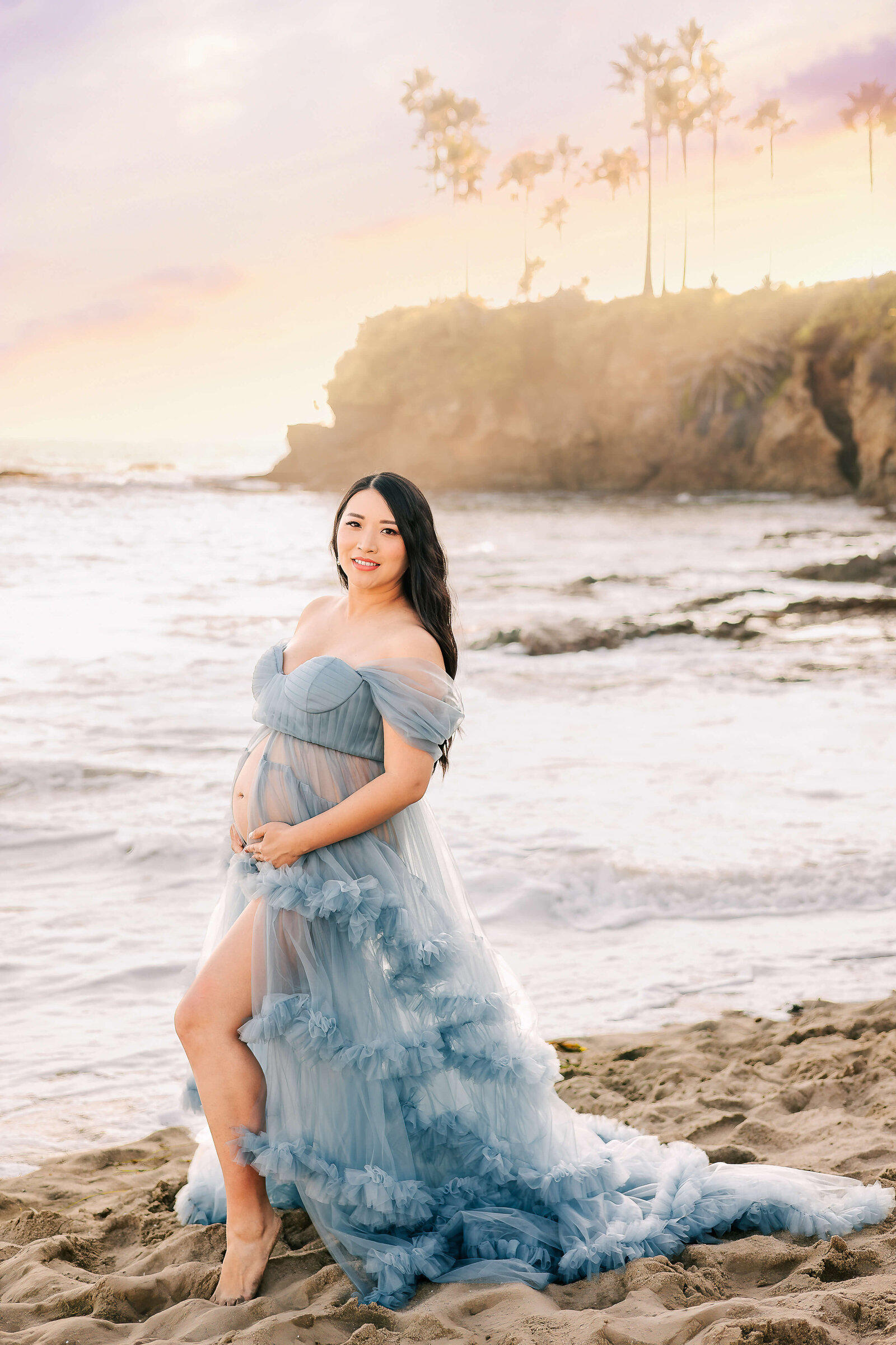 Expectant mom wearing blue ruffled  dress in Laguna Beach for maternity session by Ashley Nicole Photography.