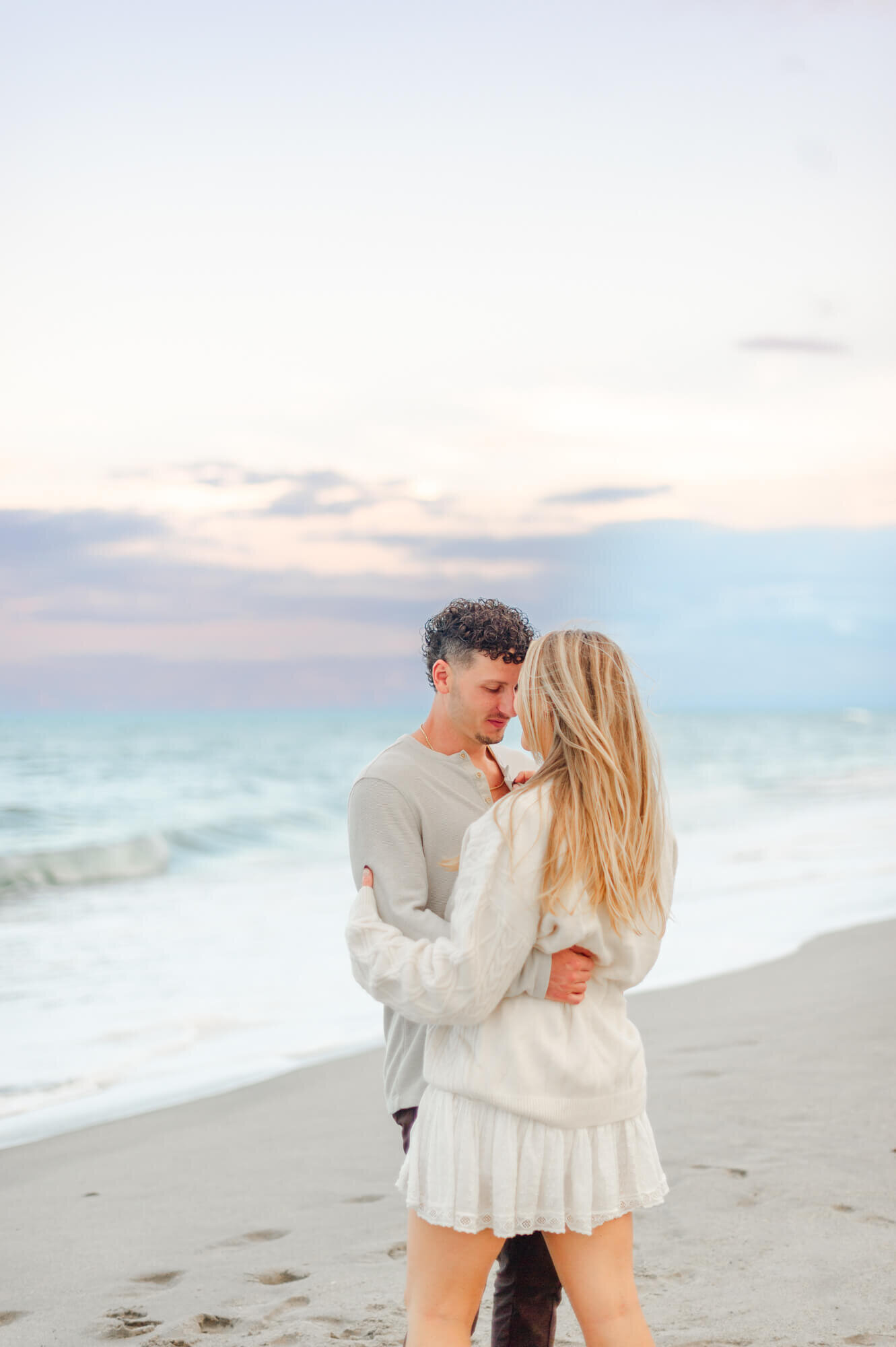Couple embracing on the beach near the shoreline while the sunset