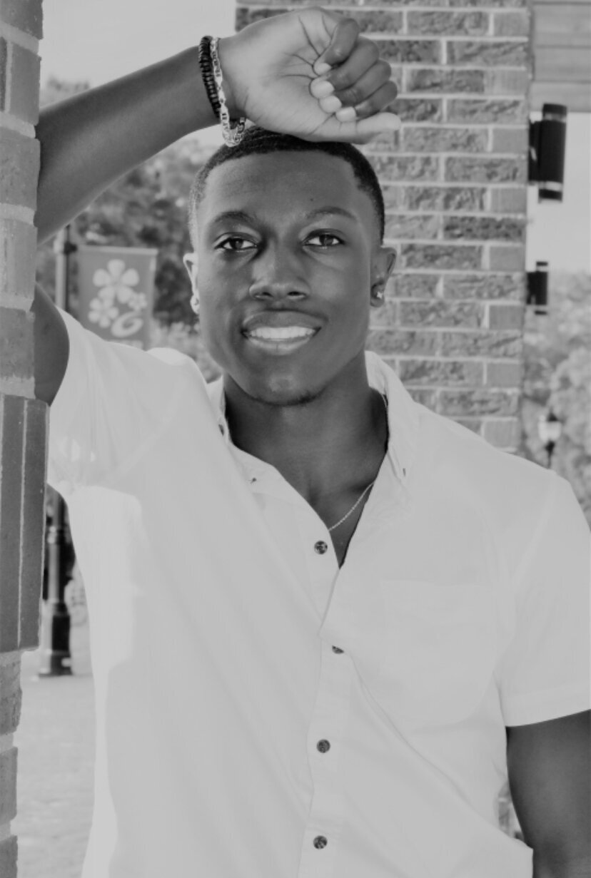 black and white photo of a senior posing for graduation photos photographed by Millz Photography in Greenville, SC