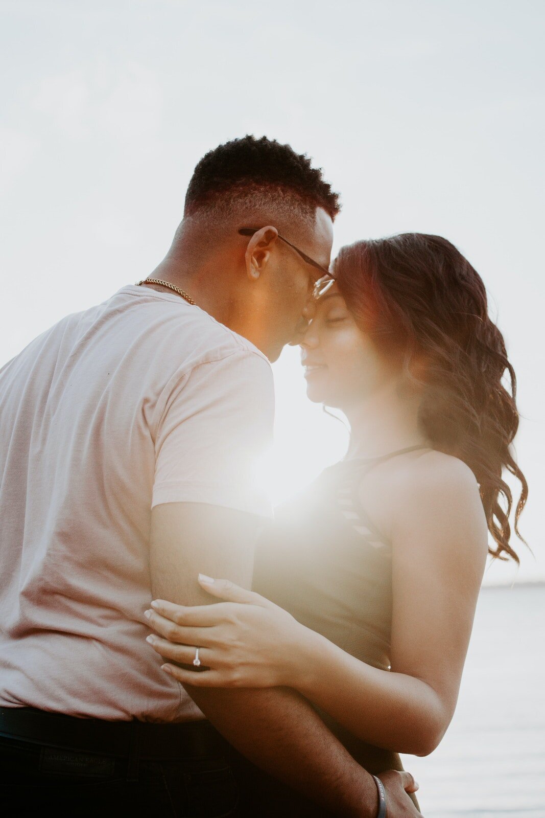 couple hugging in a warm embrace in front of the sun
