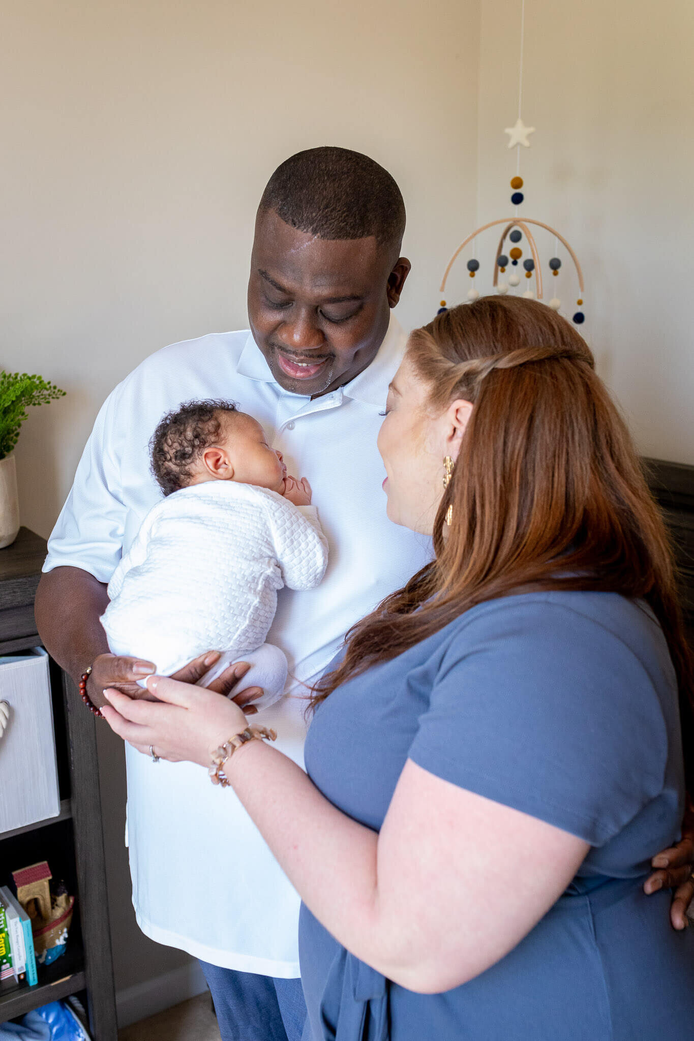 A family of three standing in their baby's nursery in Woodbridge.