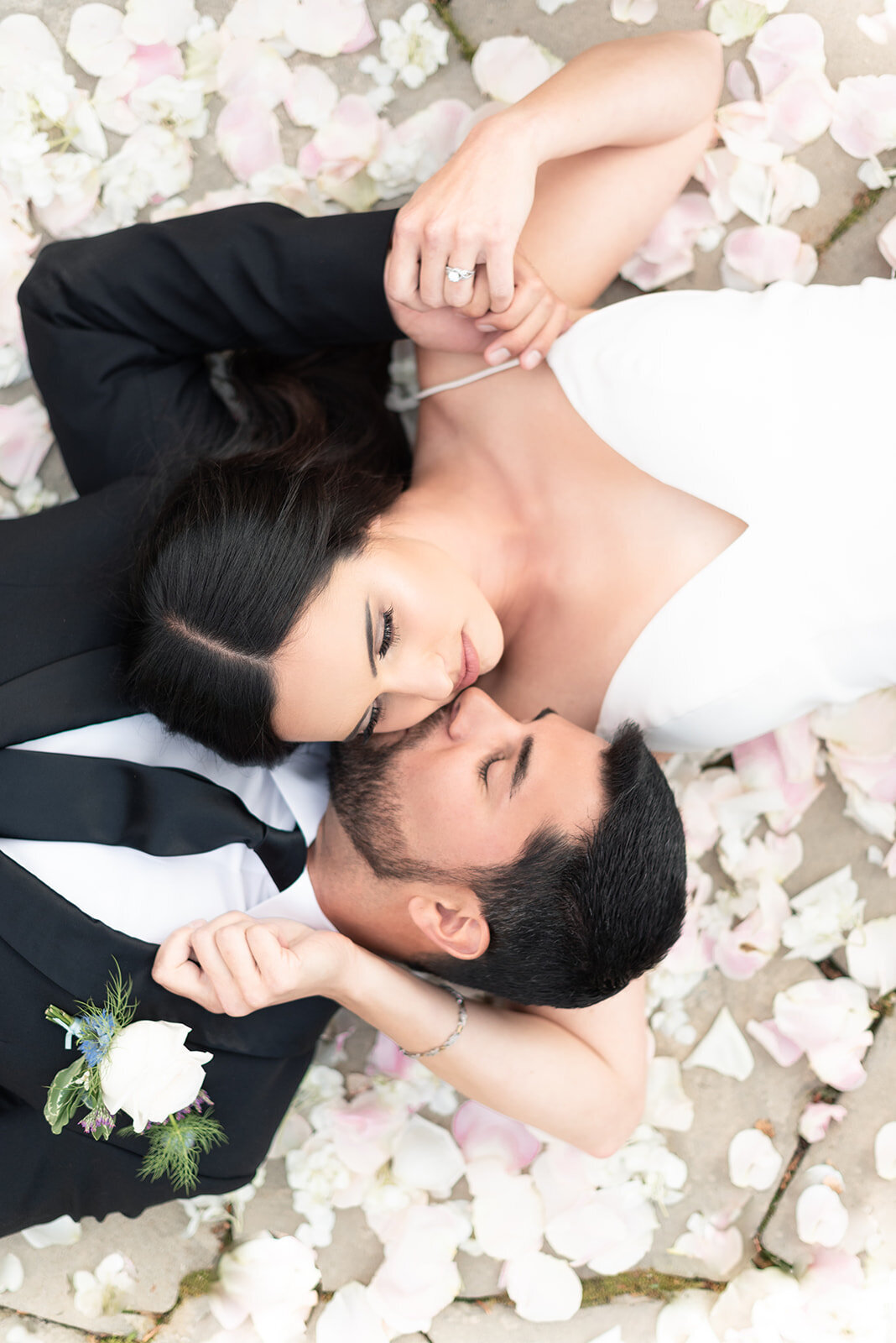 Bride and groom laying in rose petals at Cottage at Riverbend Wedding by the Best Boise Wedding Photographers