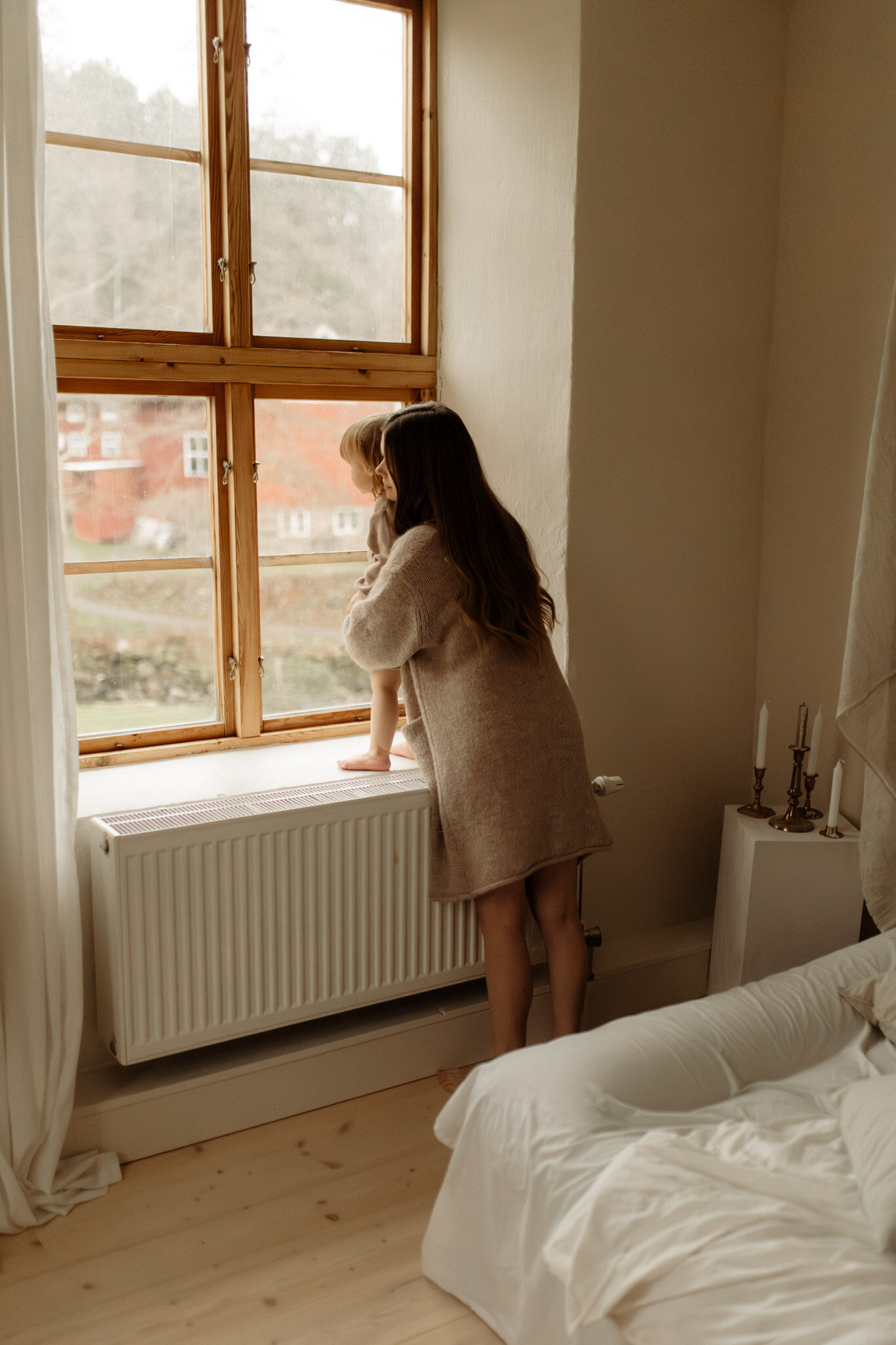 en mamma och hennes dotter kollar ut genom ett fönster