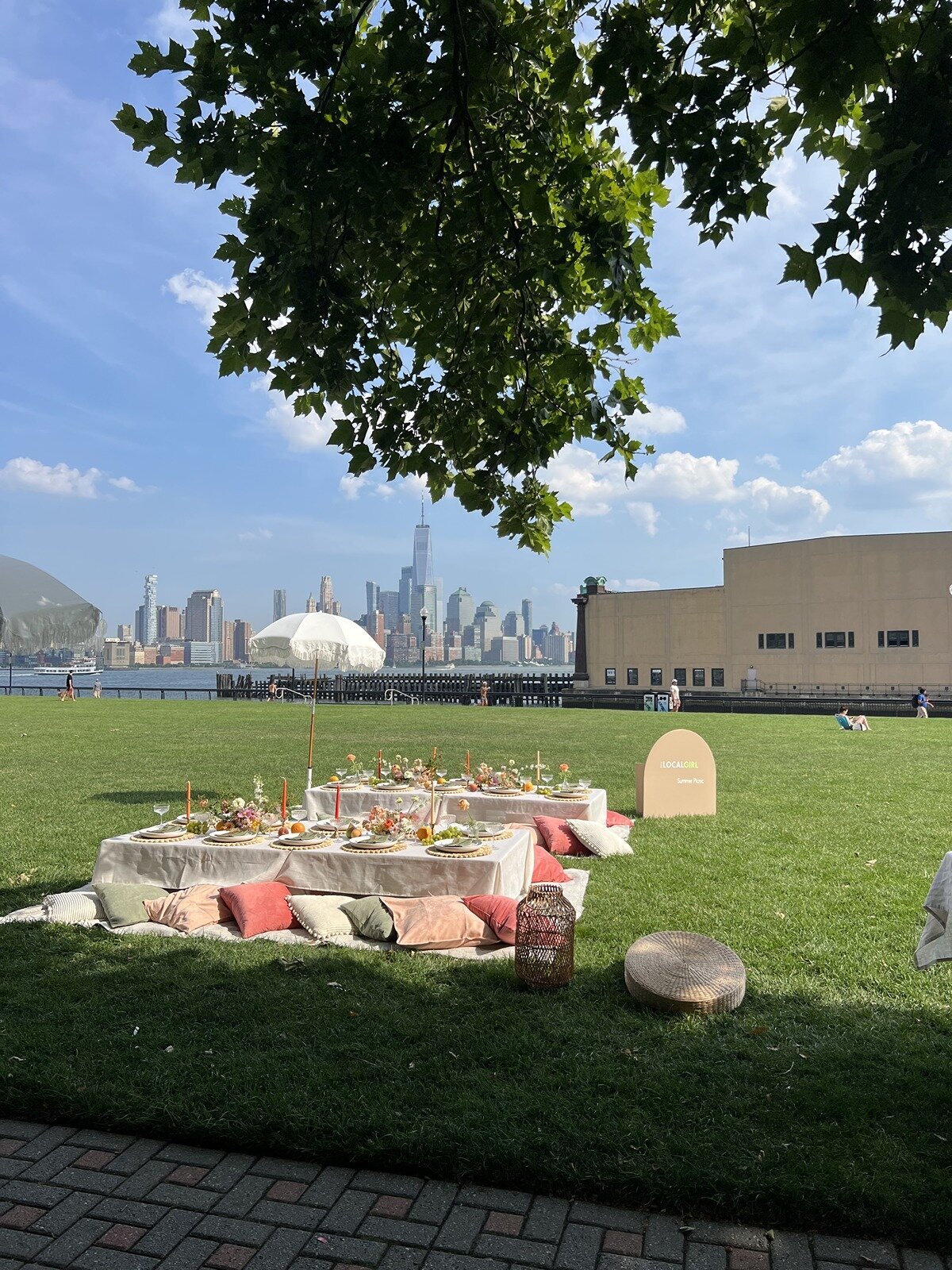 Luxury picnic setup with pastel cushions, styled tables, and skyline views of New York City, designed by Yours Truly, a wedding planner and designer in New Jersey.