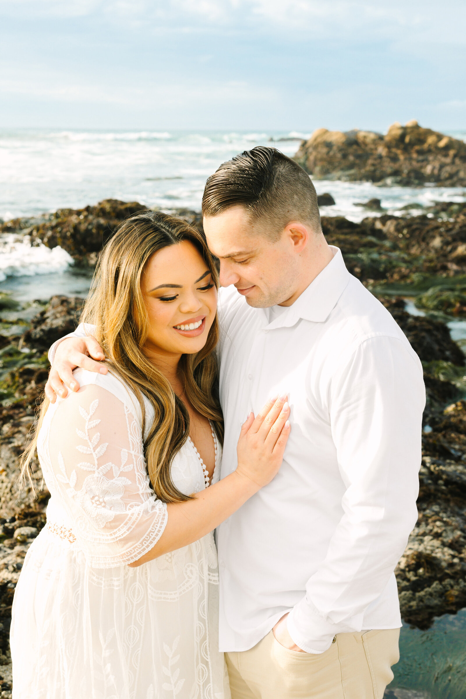 An engaged man and woman take photos on the beach in Pacific Grove, Monterey, California near Big Sur.