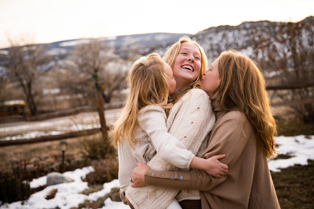a mom and her two daughters kiss each other