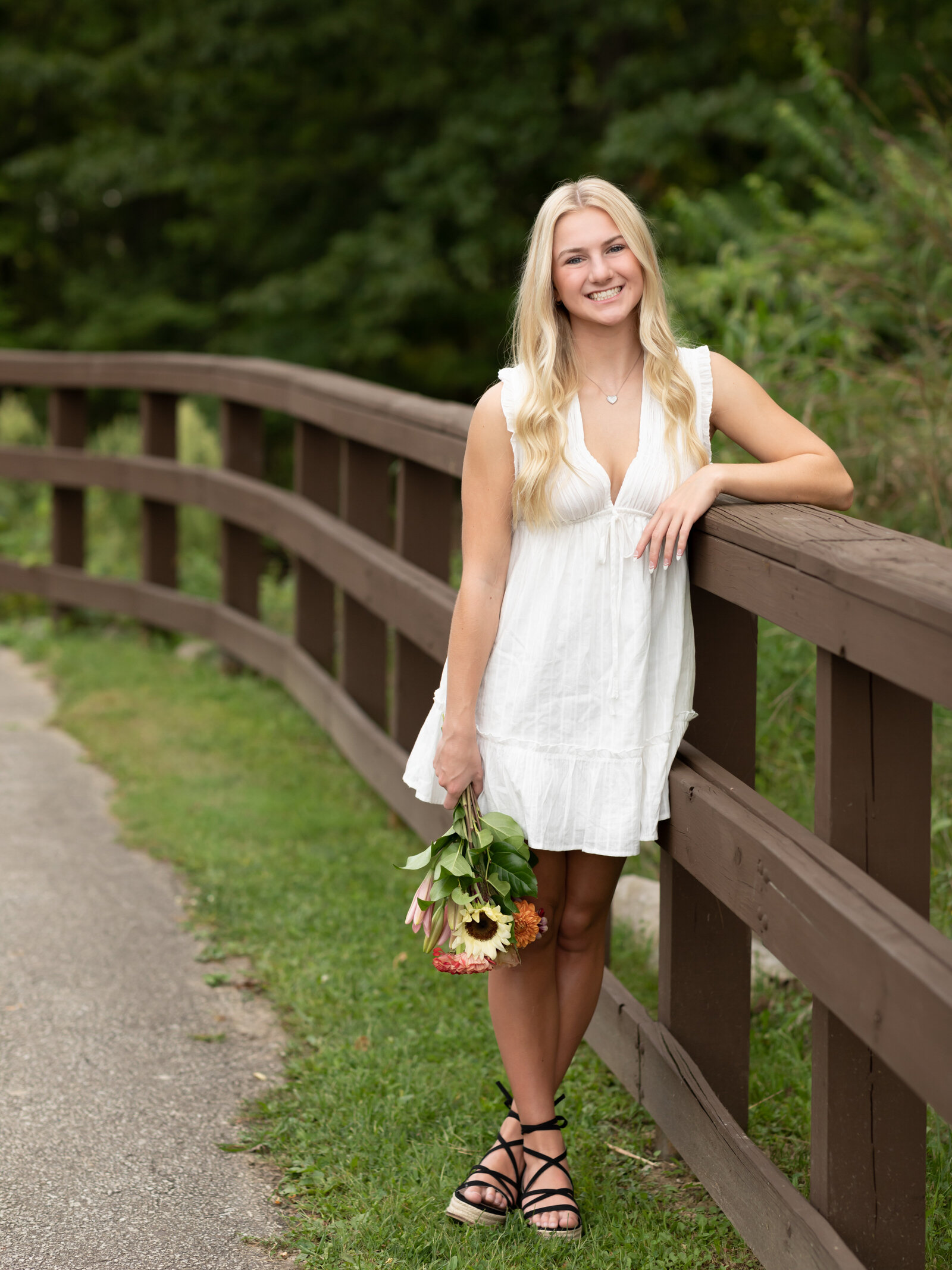 girl holding flower bouquet at park for senior pictures