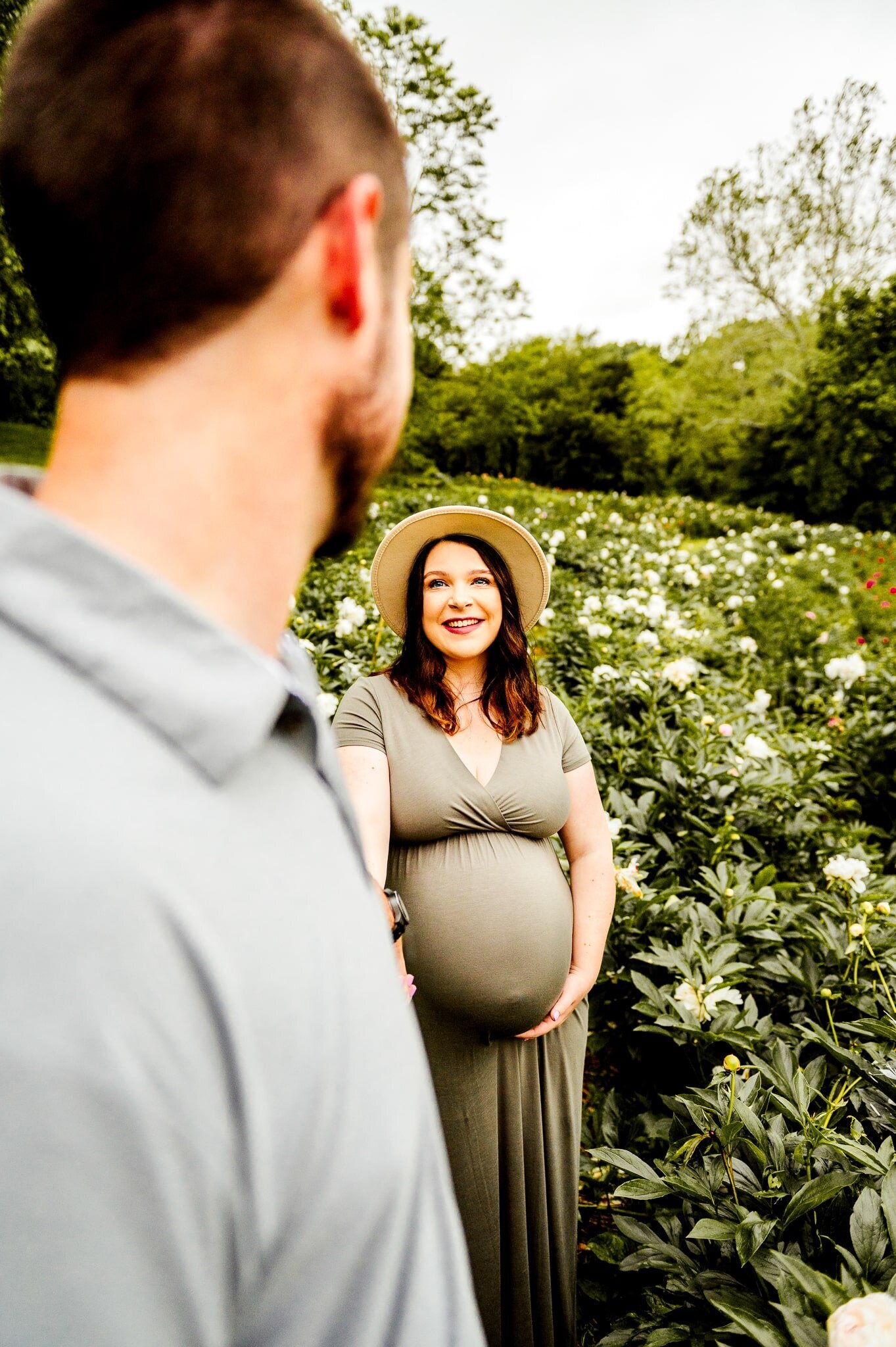 dad leading pregnant wife through a flower field