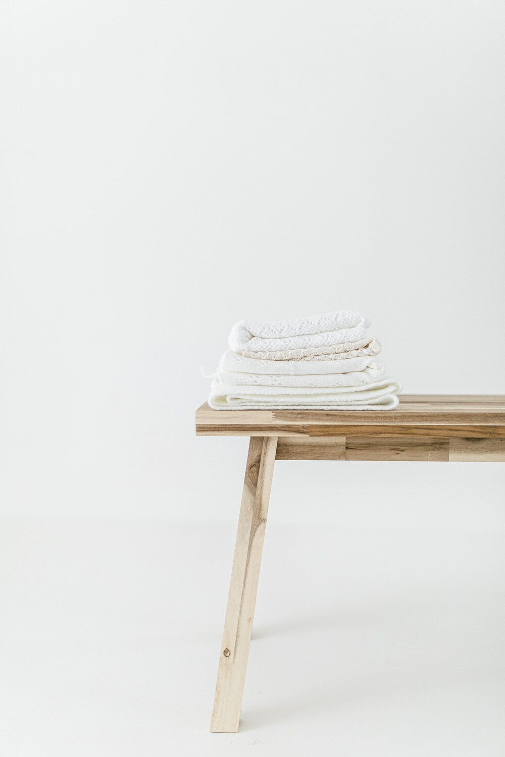 Wooden bench with blankets stacked ontop