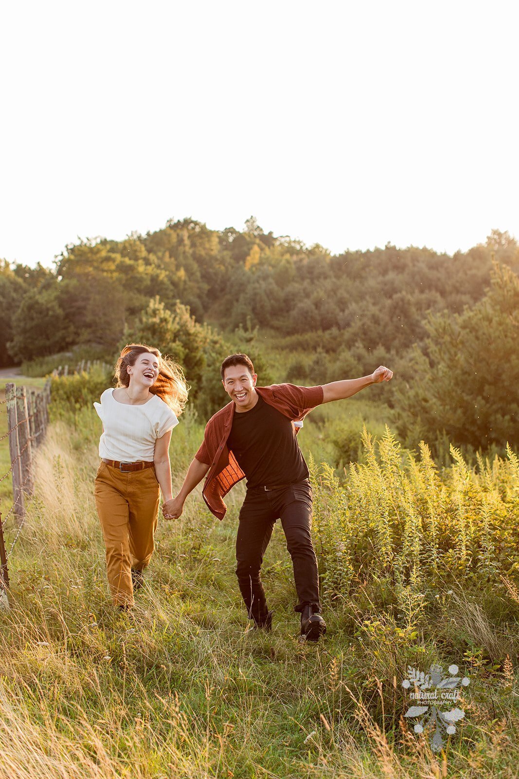 Engagement photos of a couple skipping through a field at sunset during their Boone, NC engagement session