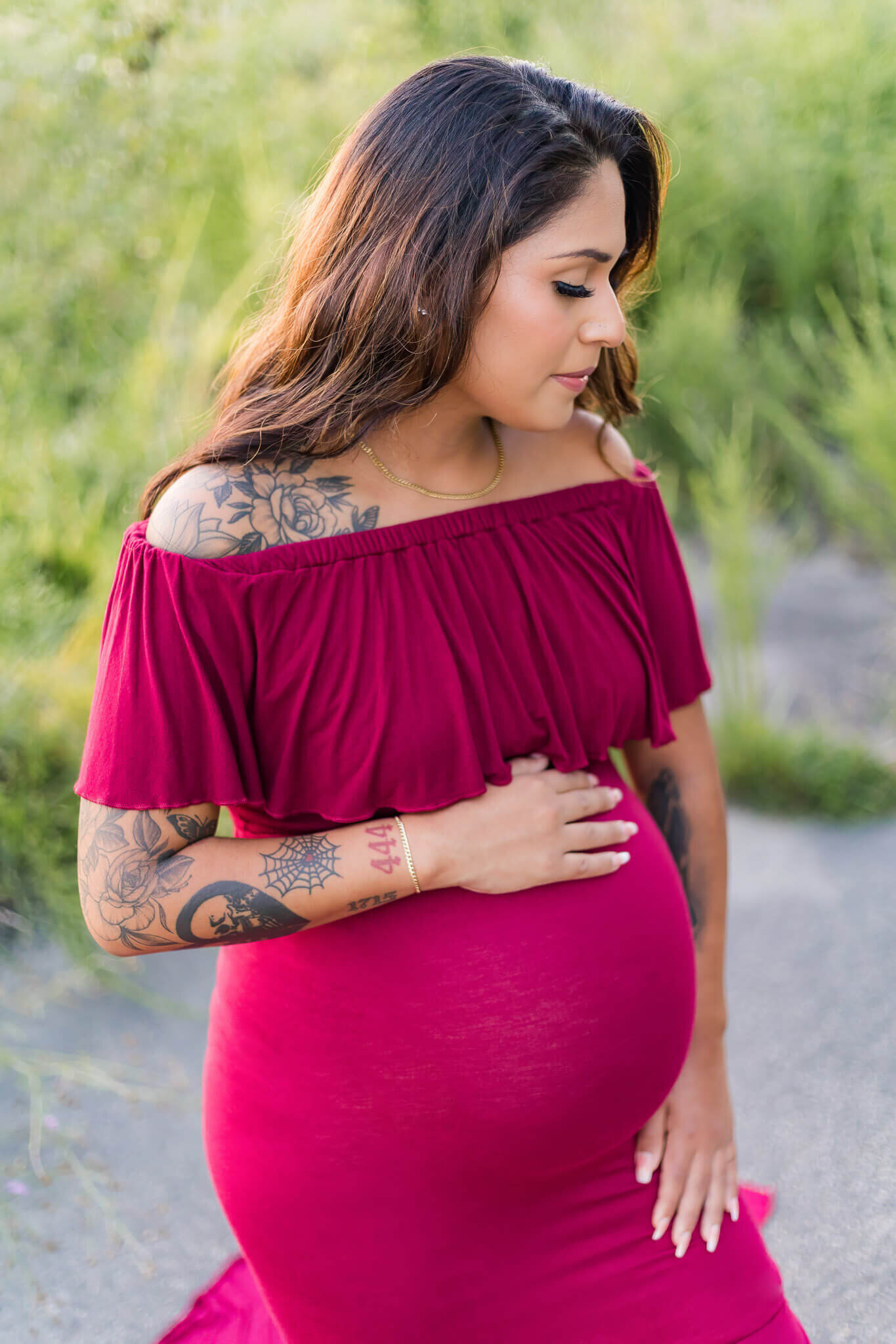 A close-up of a pregnant woman in a red dress holding her belly.