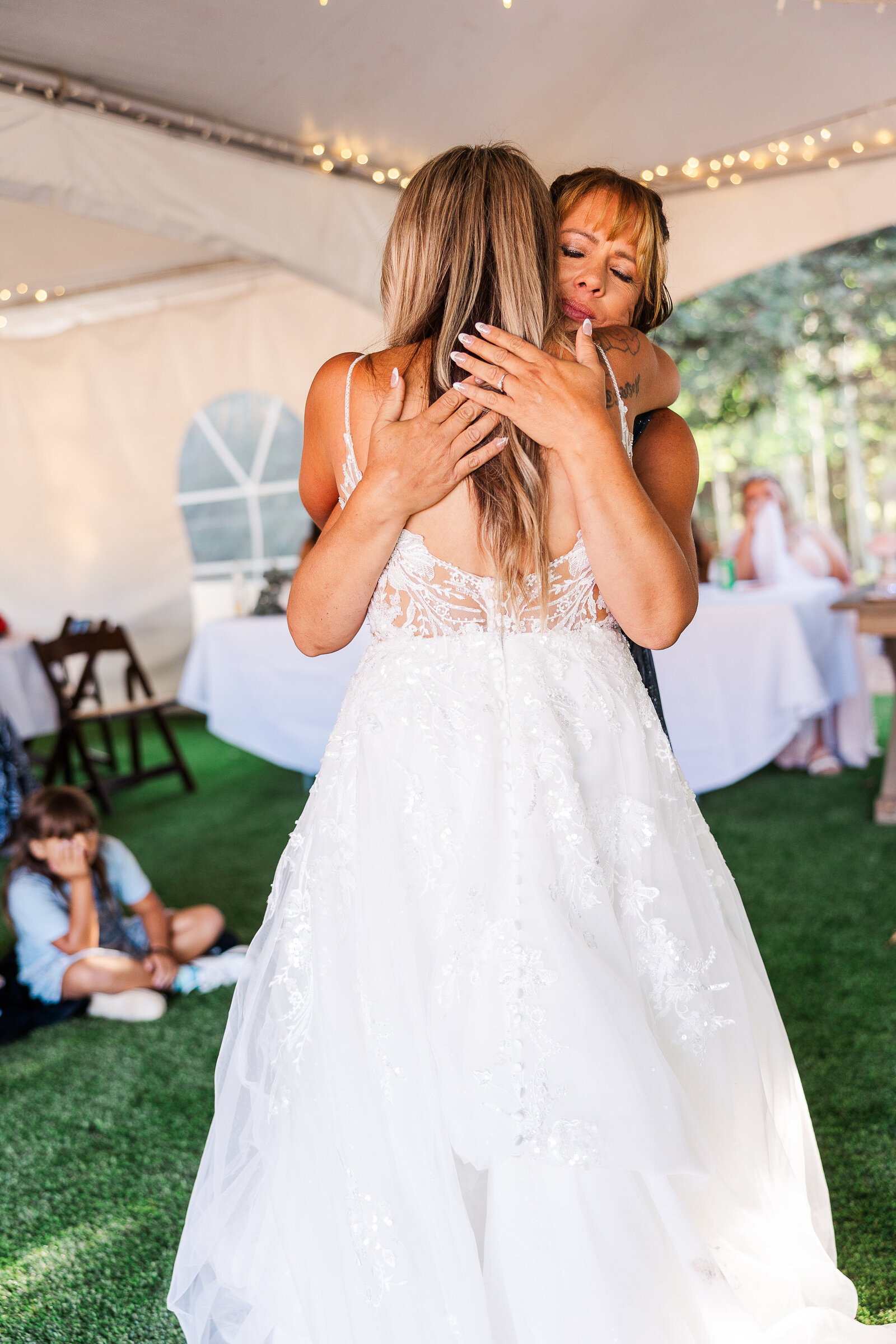 Mom hugs her daughter, the bride, at her wedding in this sweet moment