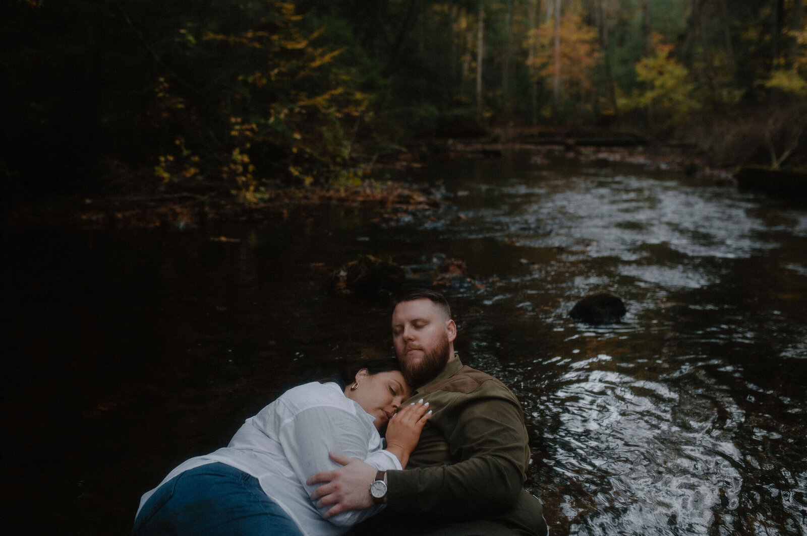 couple in the creek with november colors and romantic woods