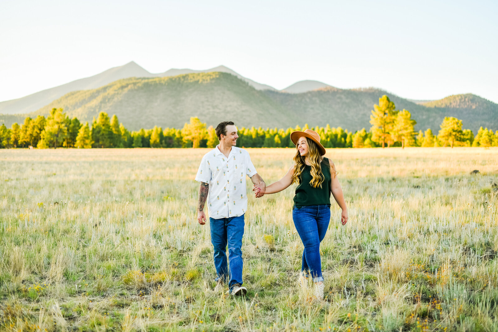Flagstaff couple holding hands engagement at Buffalo Park with San Fransisco Peaks in background mountains